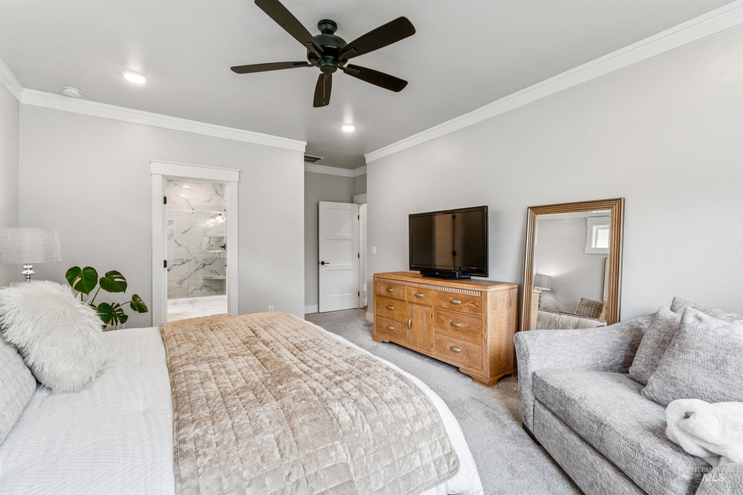 Bedroom with ornamental molding, light carpet, connected bathroom, and ceiling fan