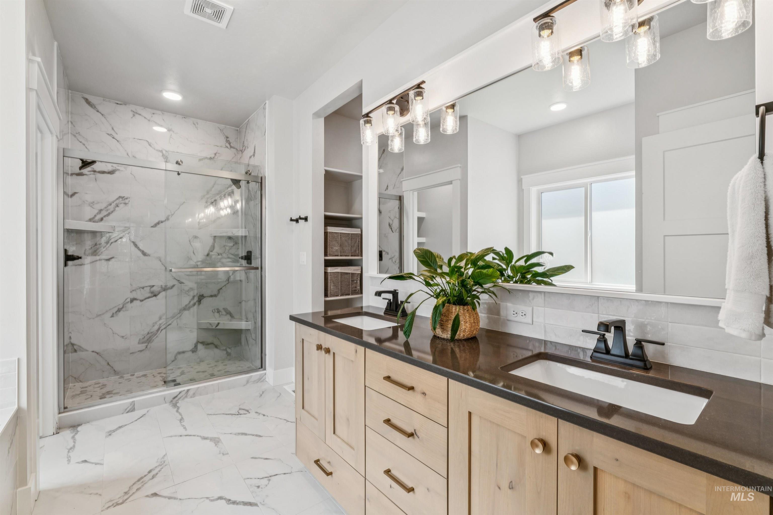 Full bathroom with a marble finish shower, double vanity, light marble finish floors, recessed lighting, and decorative backsplash