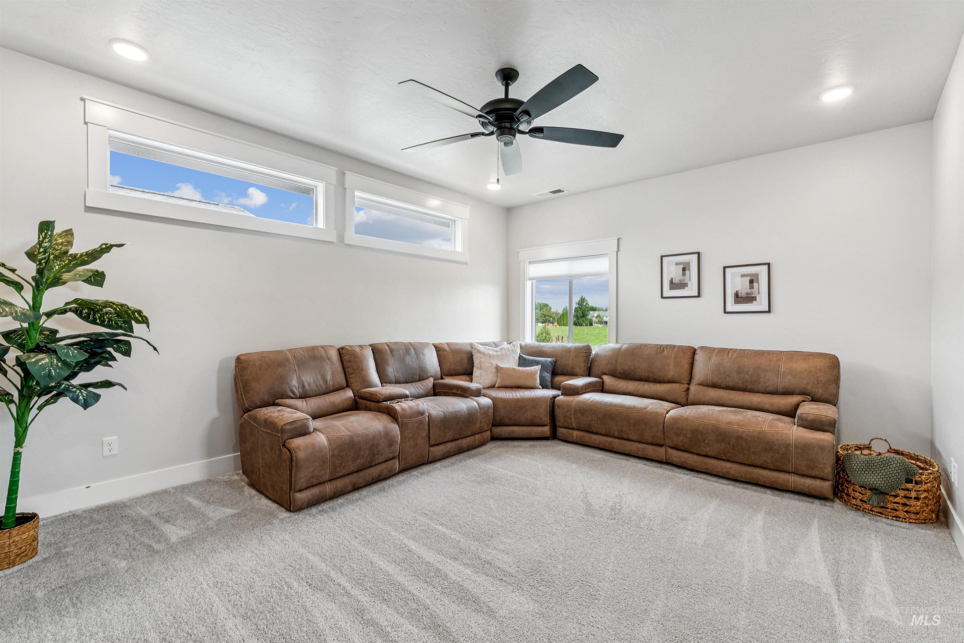 Carpeted living room with a ceiling fan and recessed lighting