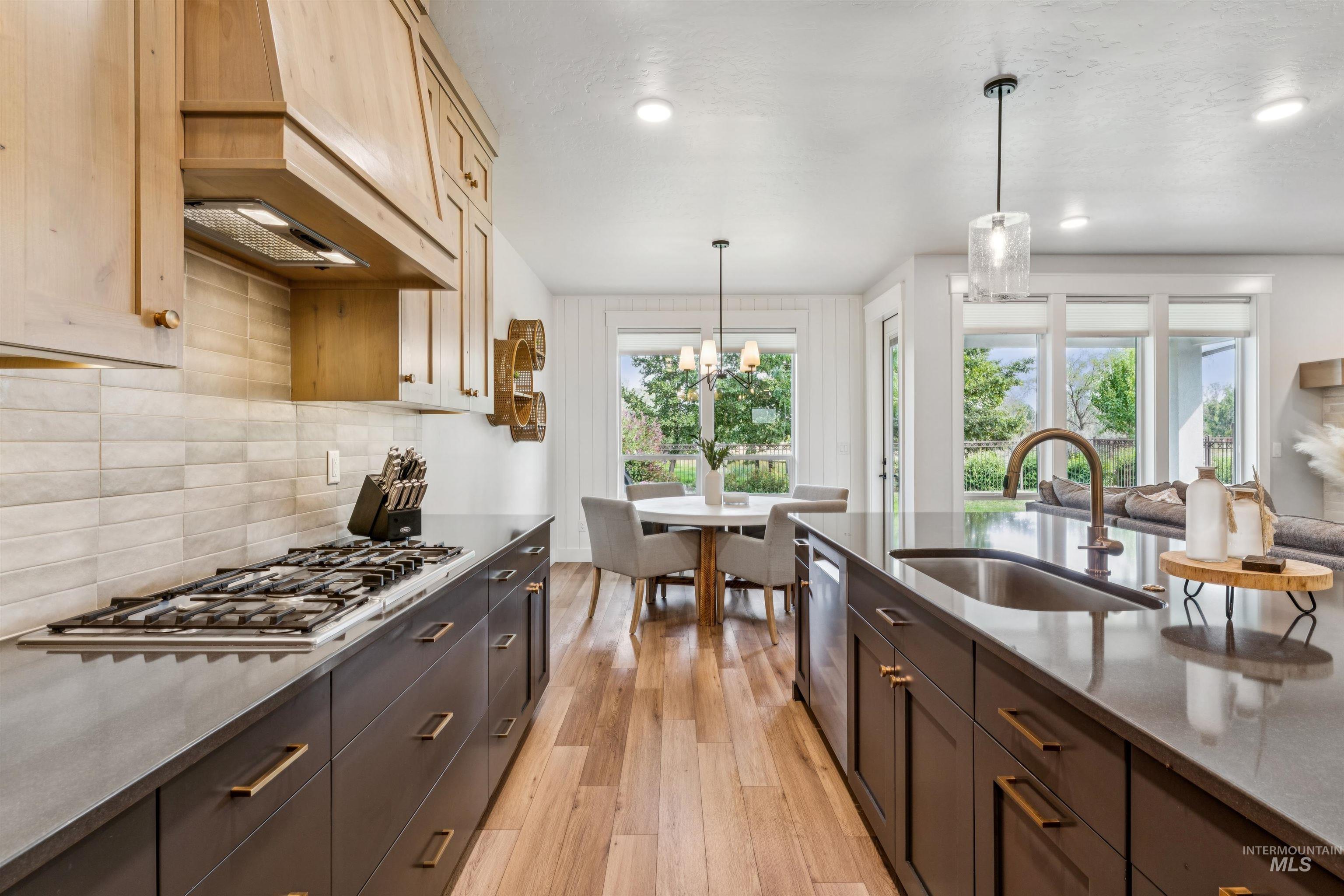 Kitchen with light wood-type flooring, hanging light fixtures, plenty of natural light, decorative backsplash, and recessed lighting