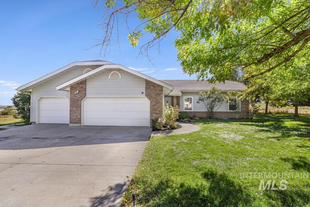 Single story home featuring brick siding, driveway, a garage, and a front lawn