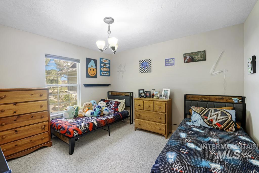 Bedroom featuring carpet floors, a textured ceiling, and a chandelier