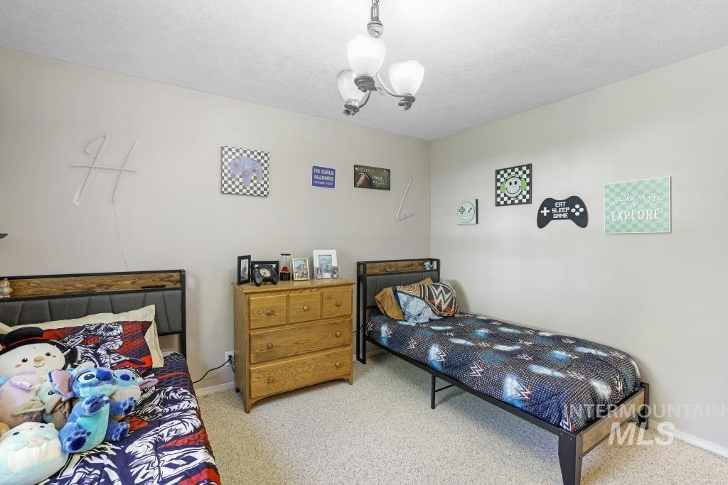 Carpeted bedroom with a chandelier and a textured ceiling