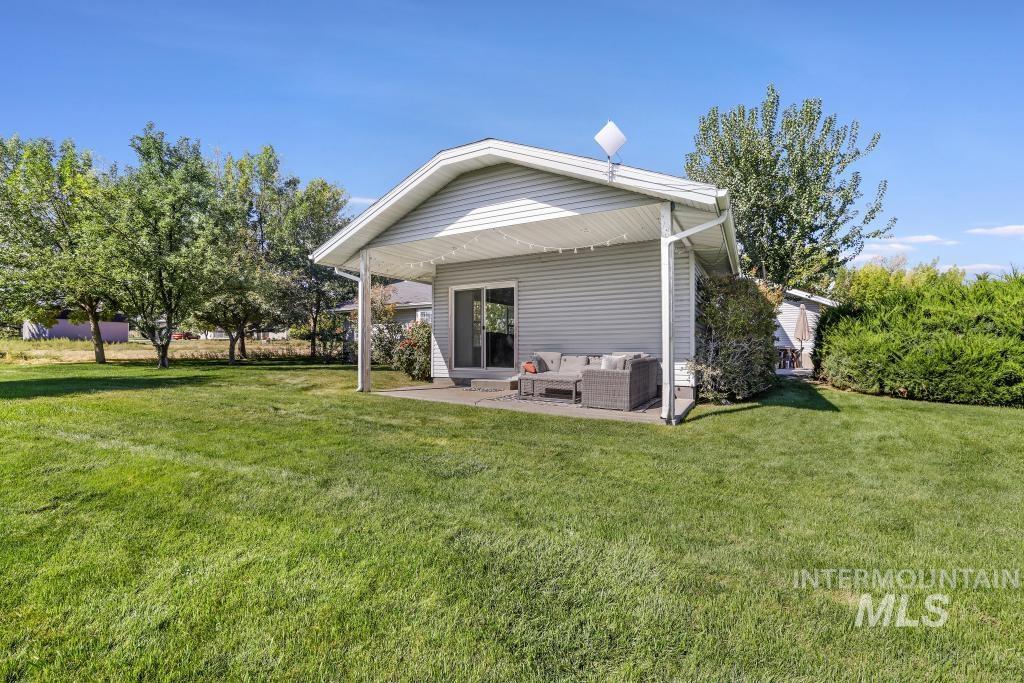 Back of property featuring an outdoor living space, a lawn, and a patio area