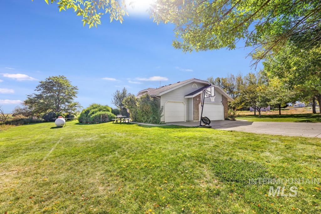 View of property exterior with driveway, a yard, and an attached garage
