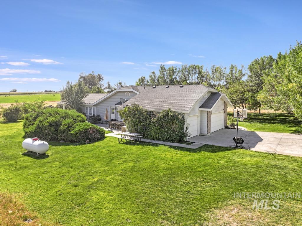 View of front of house with a front yard, concrete driveway, a shingled roof, an attached garage, and a patio area