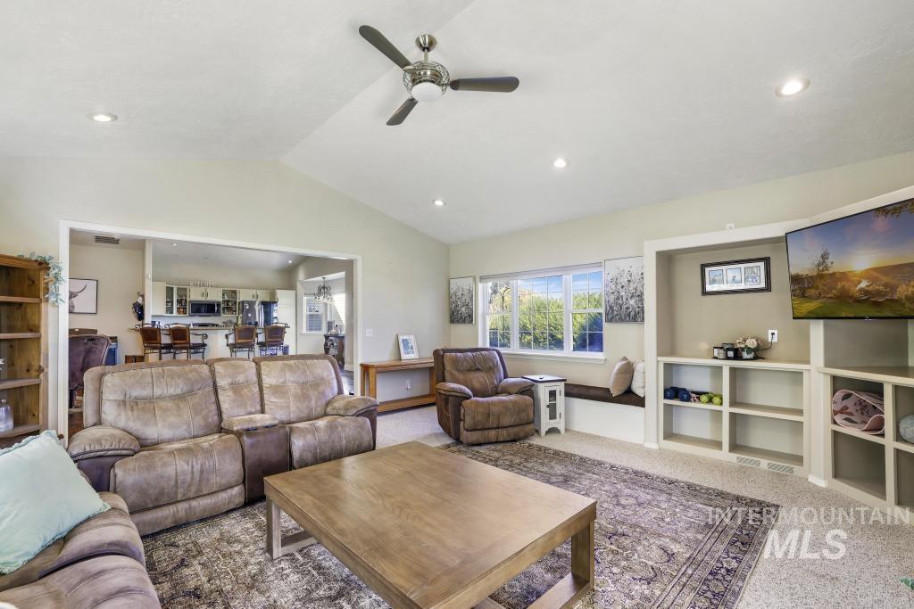 Living area featuring carpet flooring, lofted ceiling, a ceiling fan, and recessed lighting