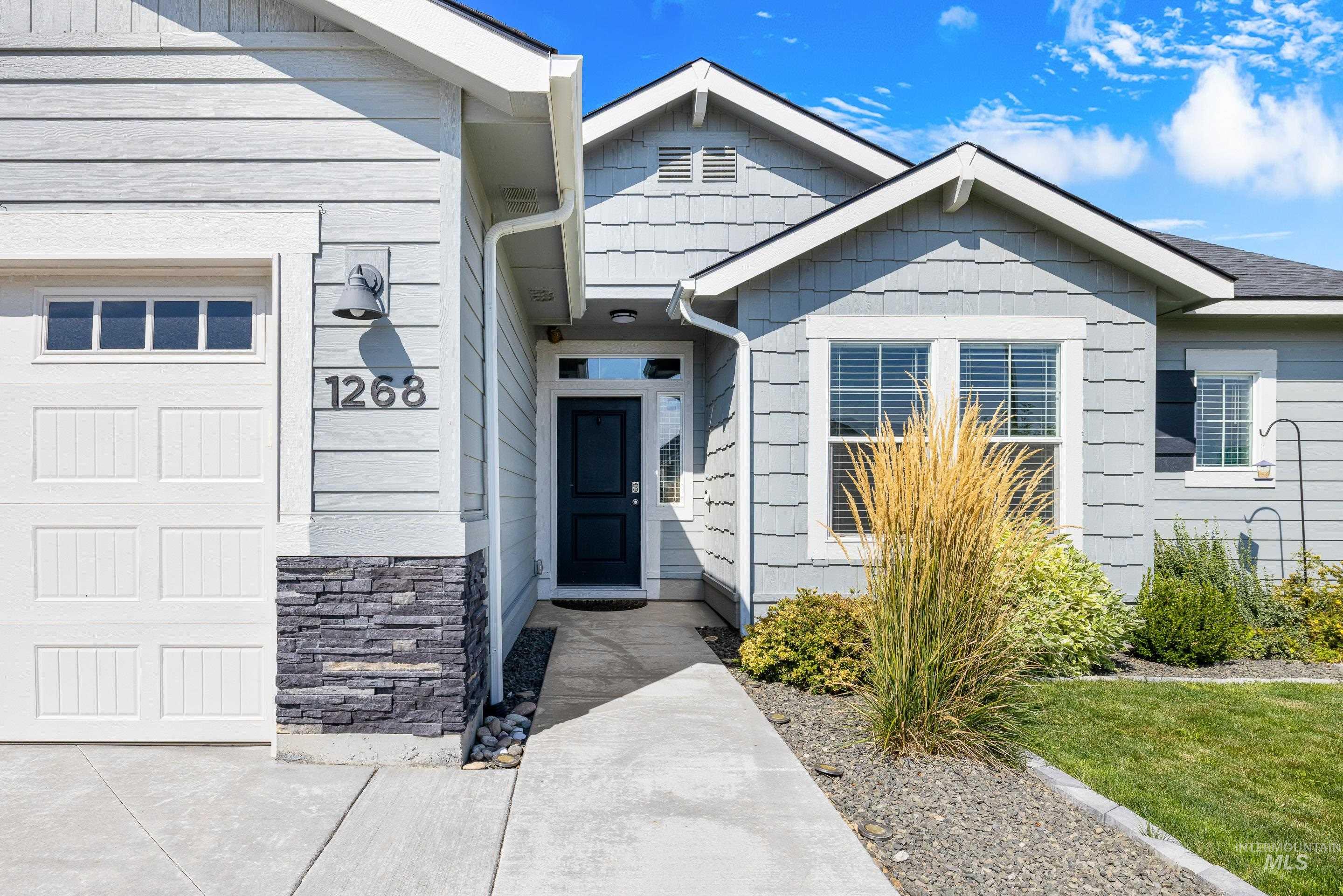 View of exterior entry featuring stone siding, a yard, and a garage