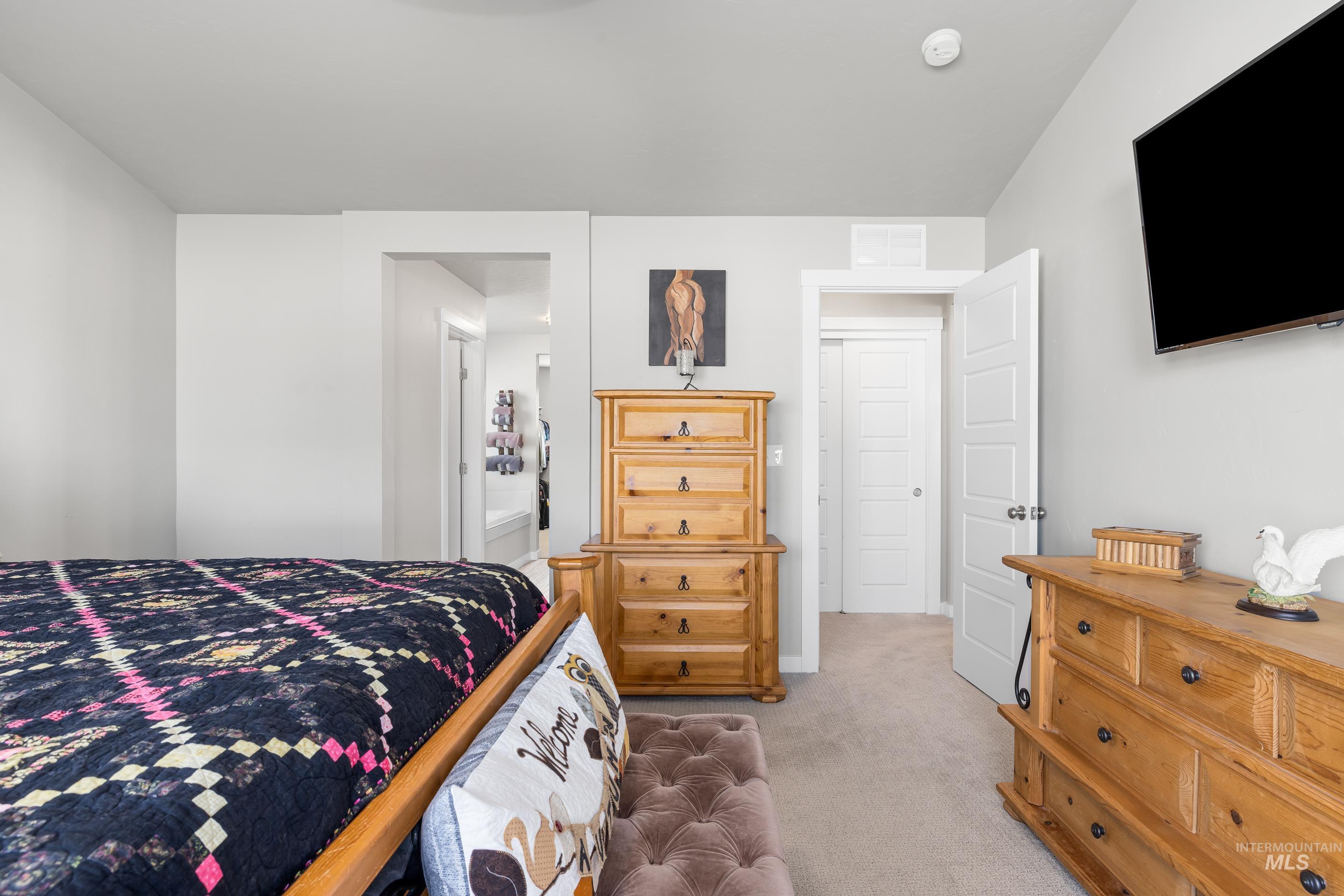 Bedroom featuring light colored carpet and ensuite bathroom