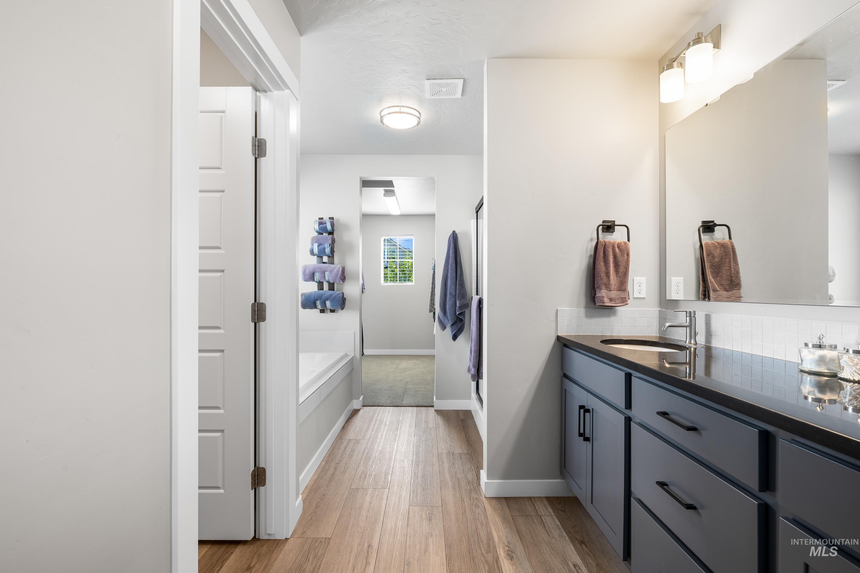 Bathroom featuring vanity, a garden tub, light wood finished floors, and a shower stall