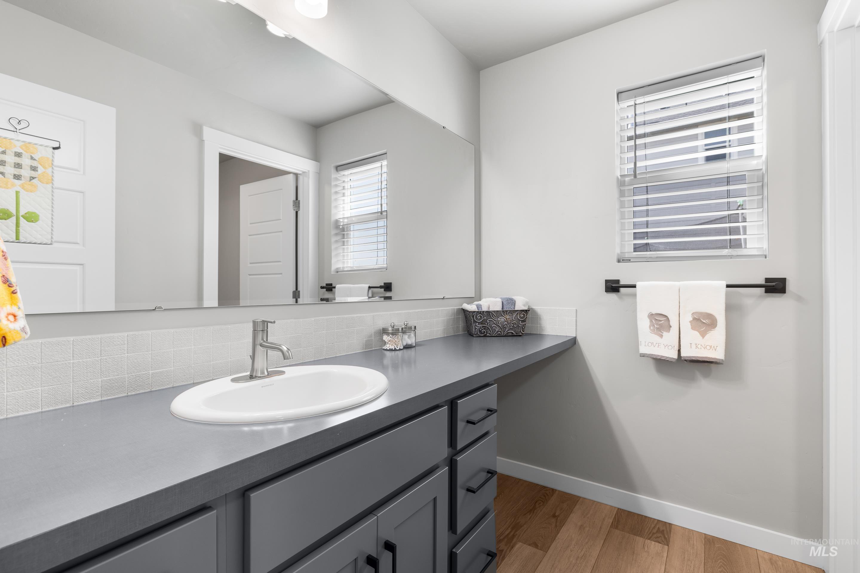 Bathroom featuring light wood-style floors, vanity, and backsplash