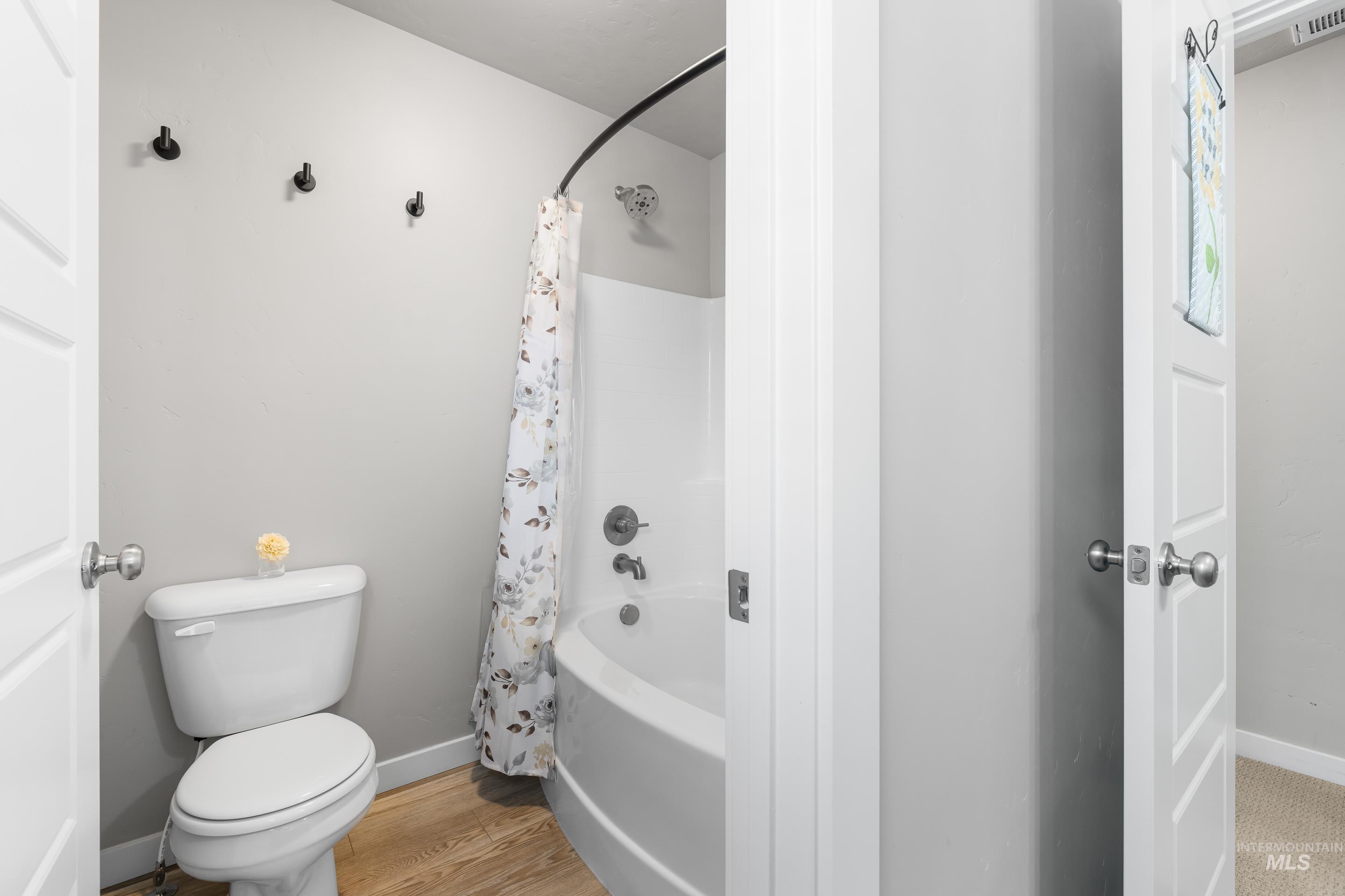 Bathroom with shower / bath combo and light wood-type flooring