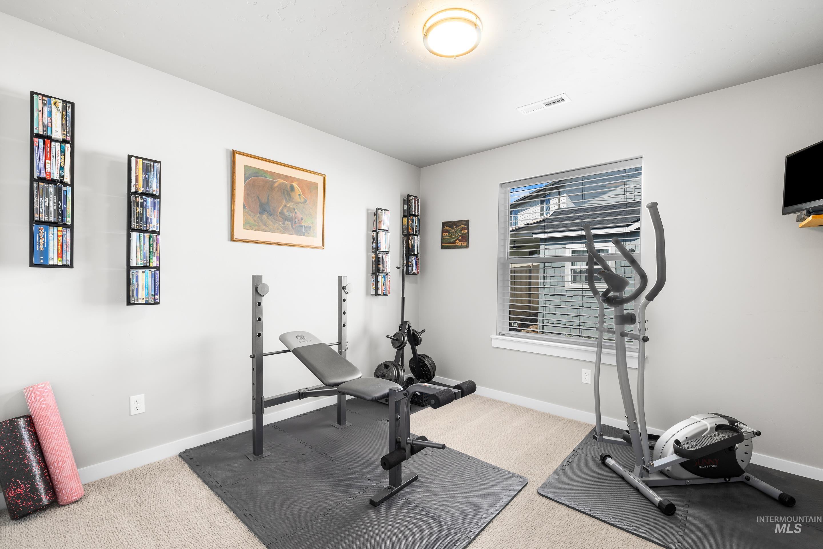 Exercise room with baseboards and light colored carpet