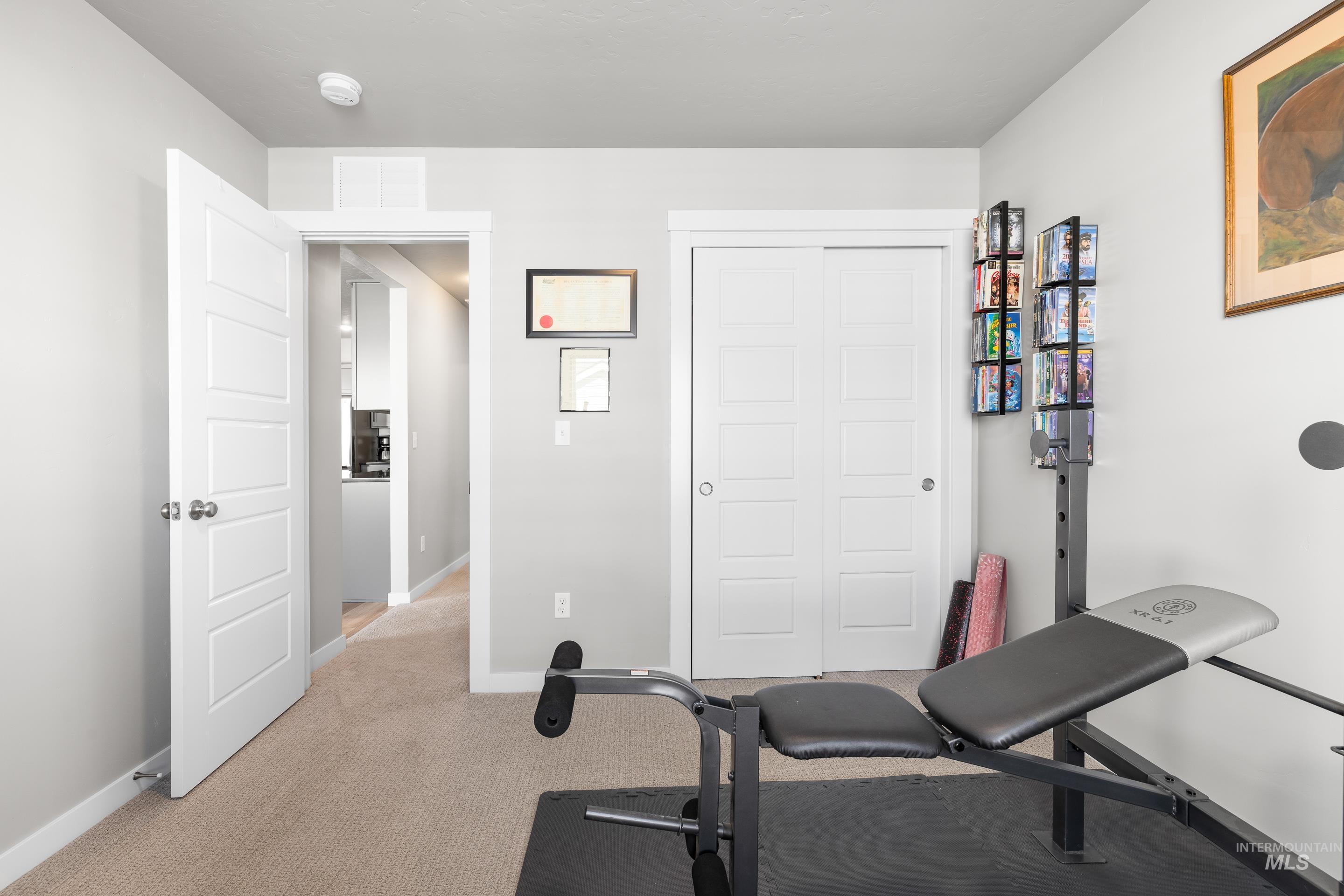 Workout room with light carpet and baseboards