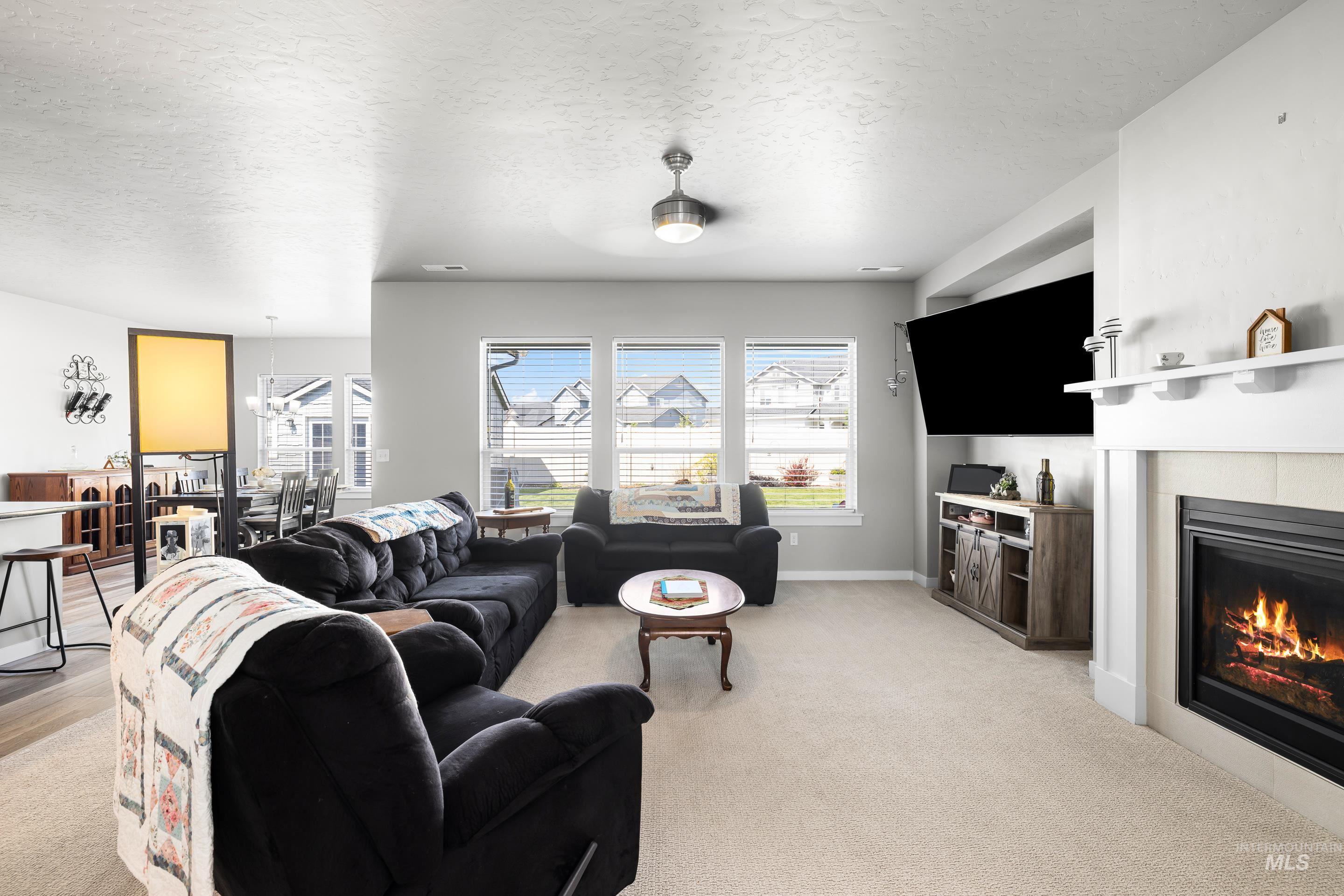 Living area featuring a textured ceiling, a tile fireplace, light colored carpet, and a chandelier
