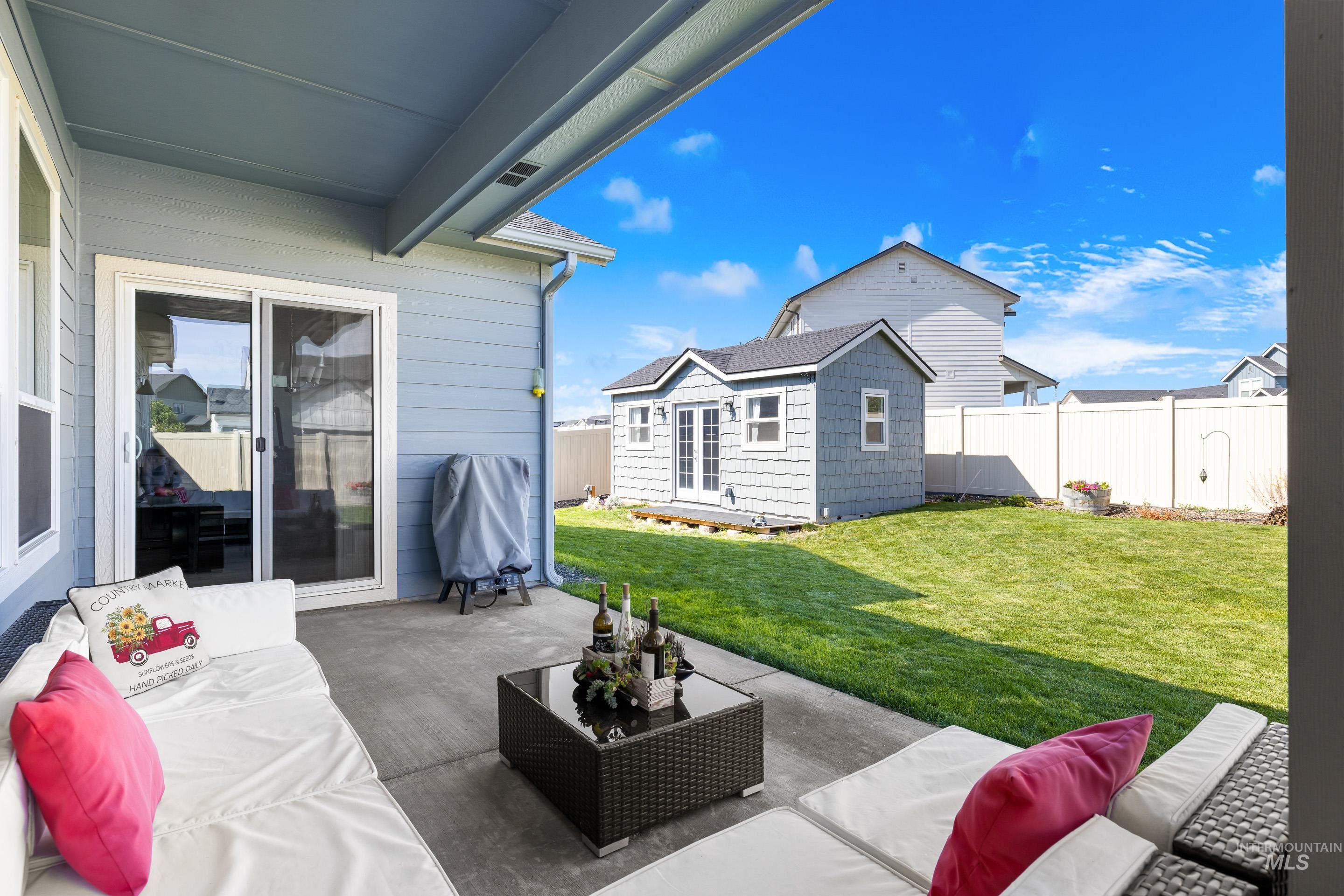 Fenced backyard with outdoor lounge area, a patio, an outdoor structure, and grilling area