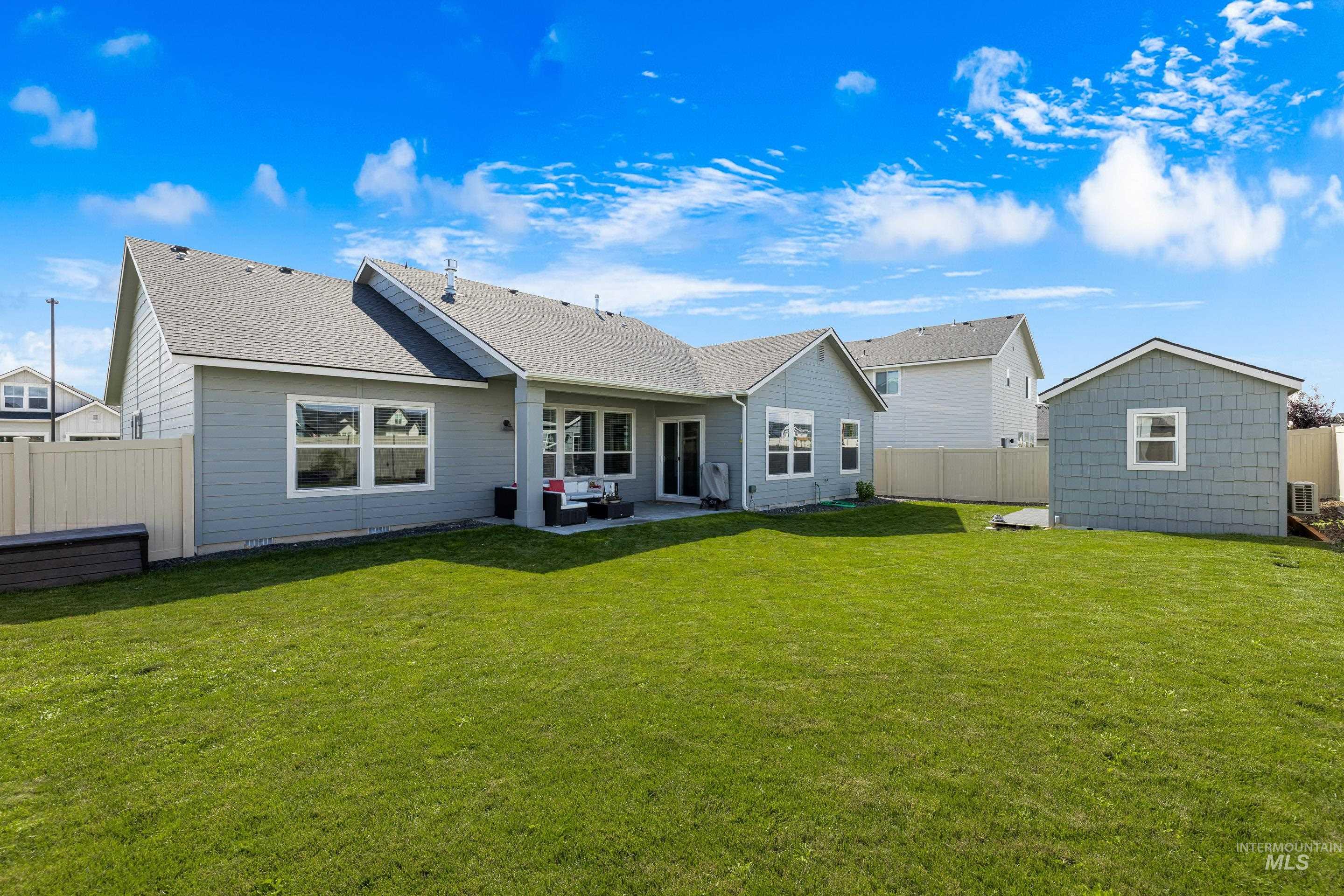 Rear view of house with a patio, a shingled roof, a fenced backyard, and an outdoor structure