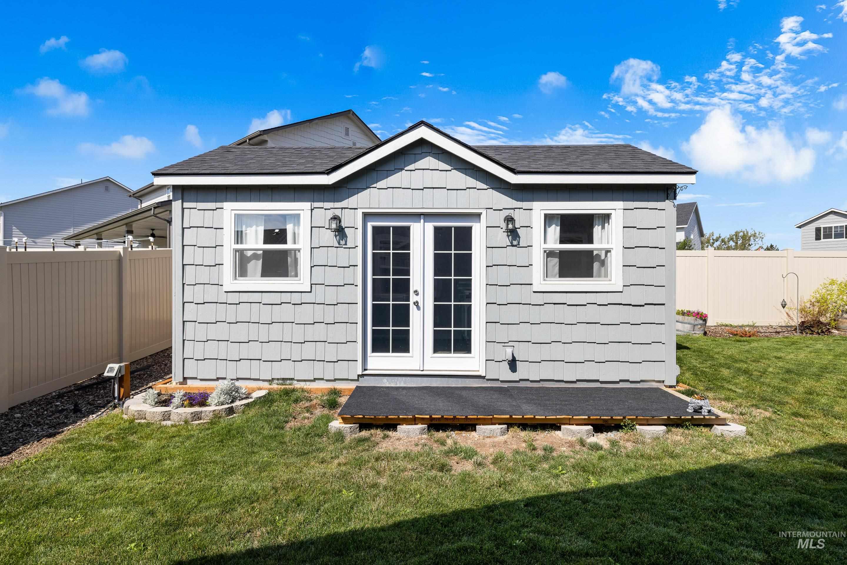 Rear view of property with a fenced backyard, roof with shingles, and french doors