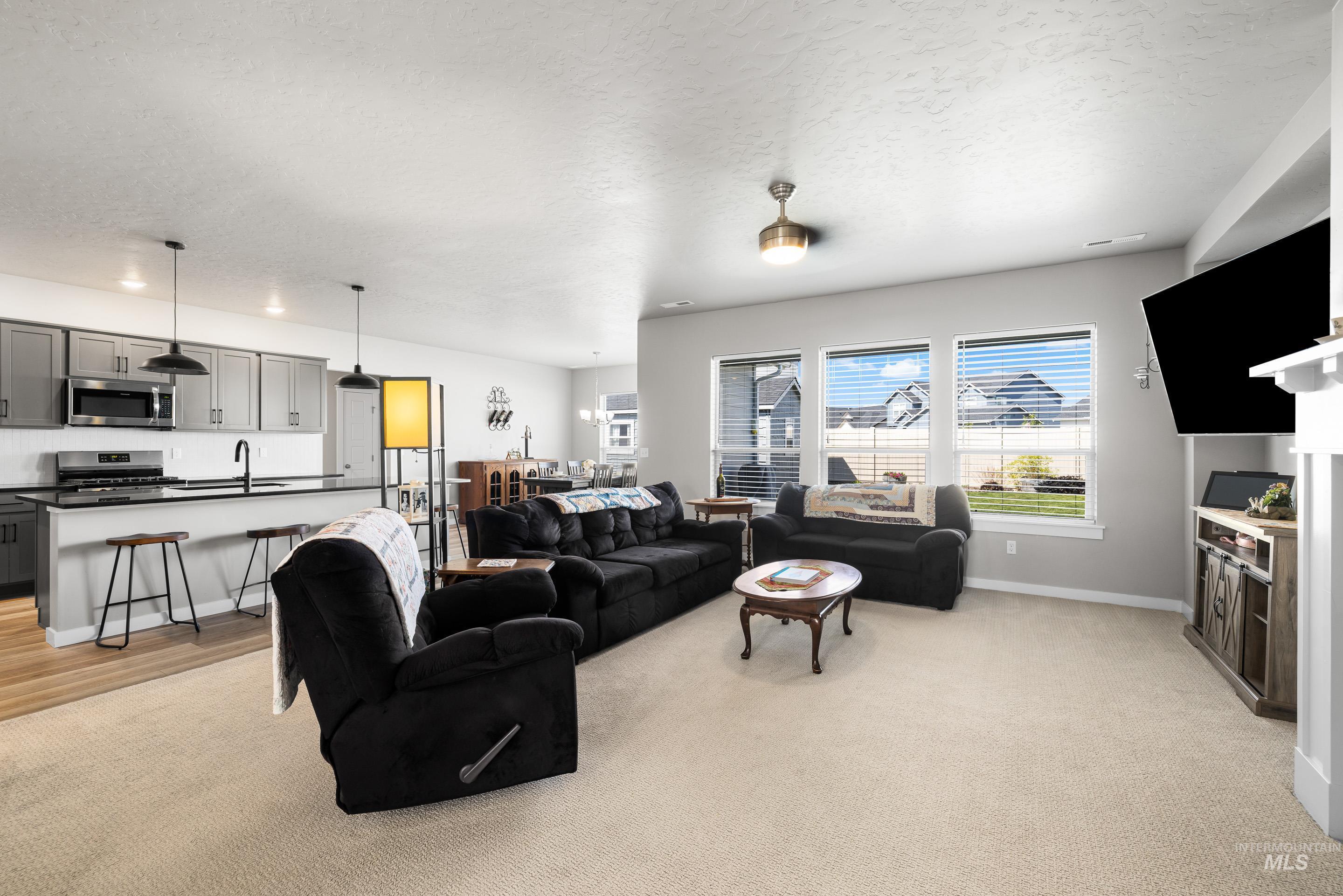 Living area with a textured ceiling and light colored carpet
