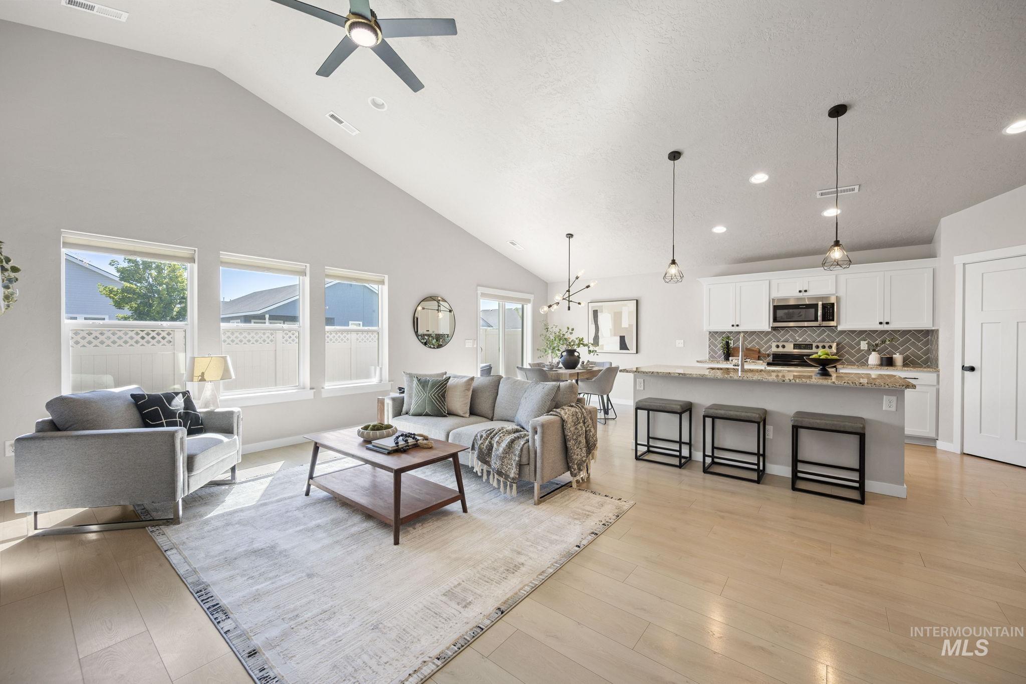 Living area with high vaulted ceiling, light wood-style flooring, healthy amount of natural light, recessed lighting, and a ceiling fan