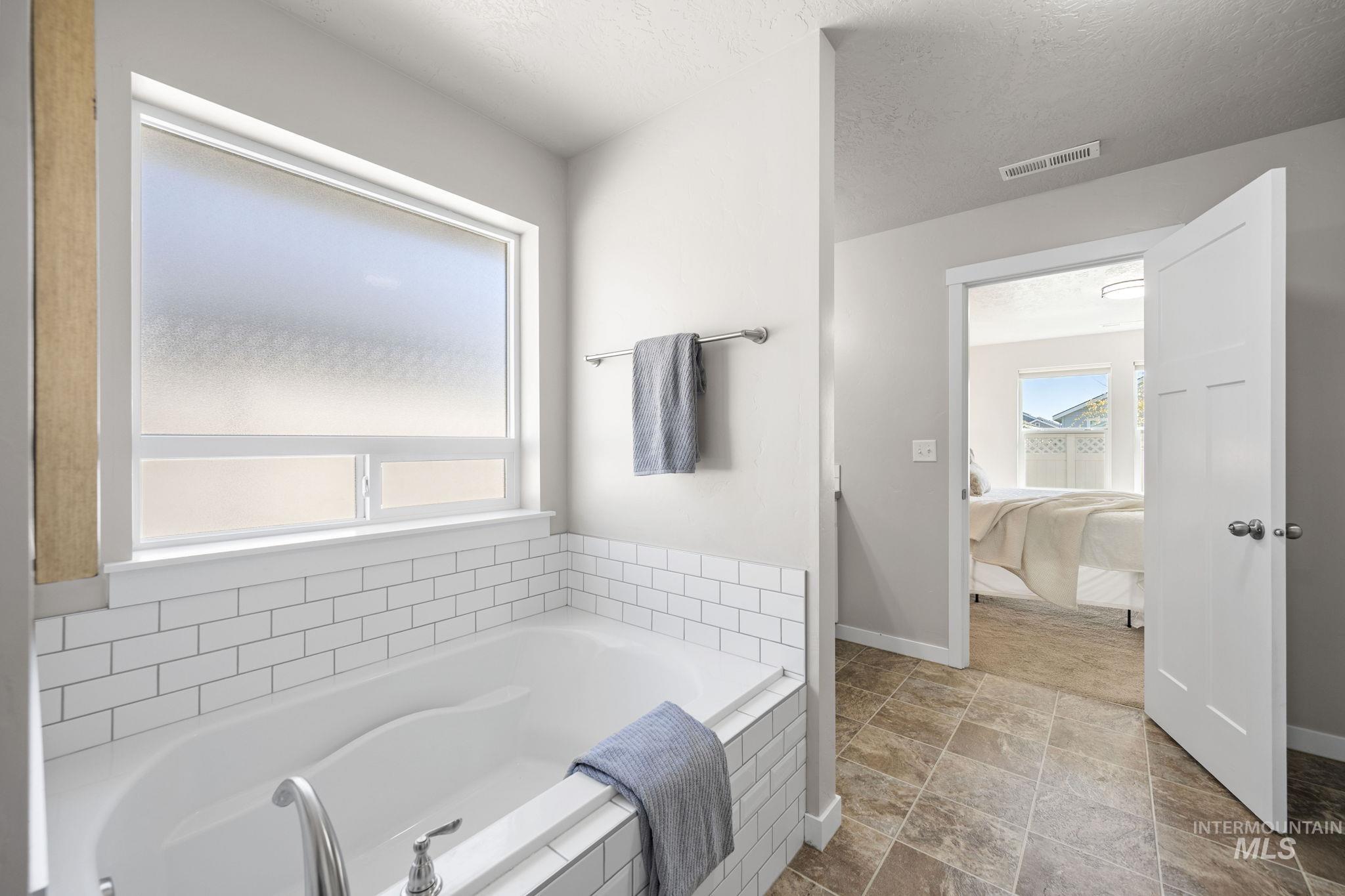 Ensuite bathroom featuring a bath and a textured ceiling
