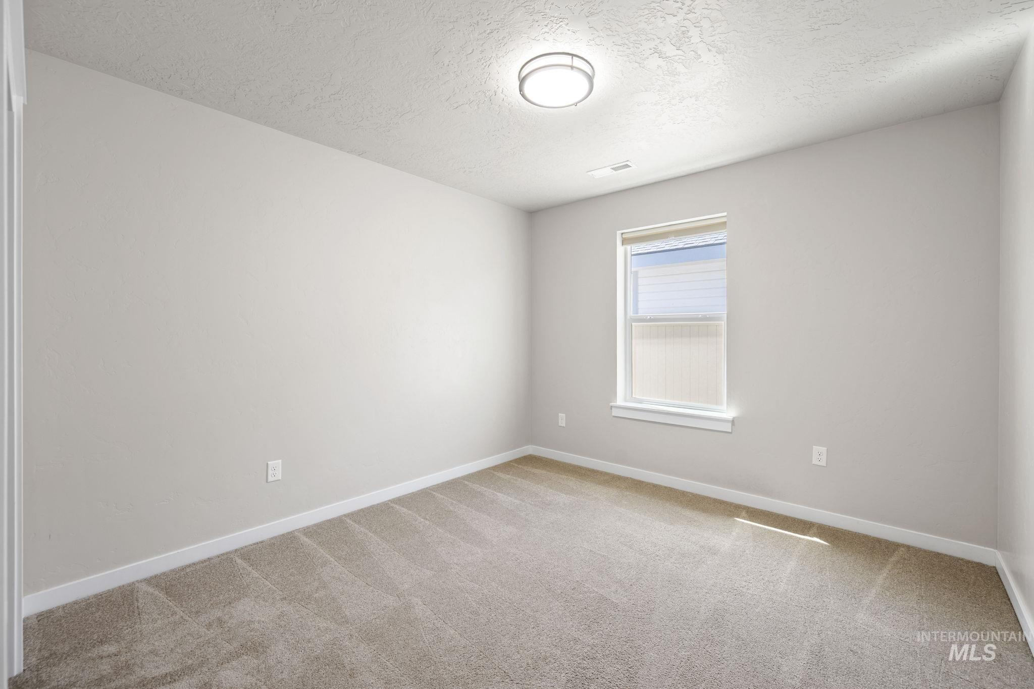 Unfurnished bedroom featuring a textured ceiling, a closet, and light colored carpet