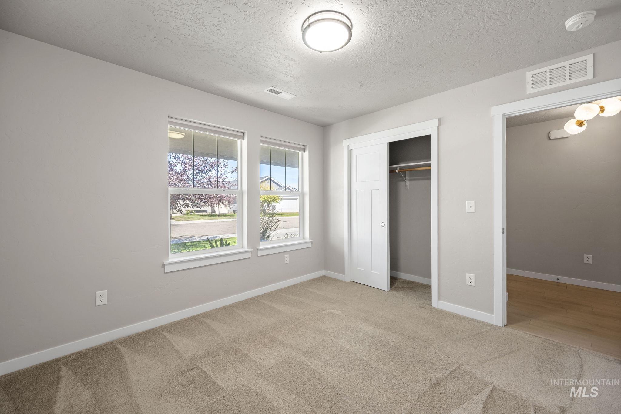 Unfurnished bedroom featuring light colored carpet, a closet, and a textured ceiling