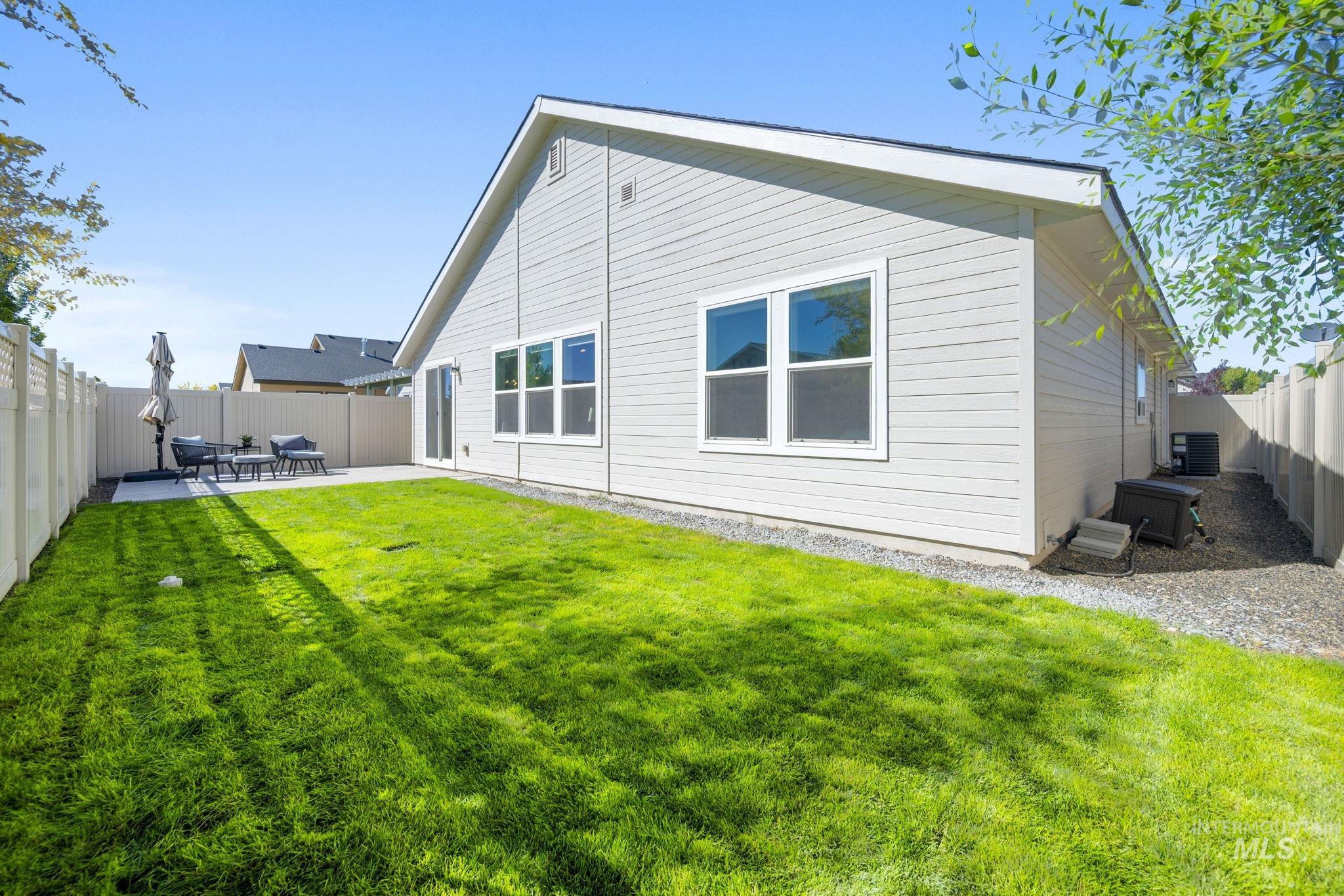 Rear view of house with a fenced backyard and a patio