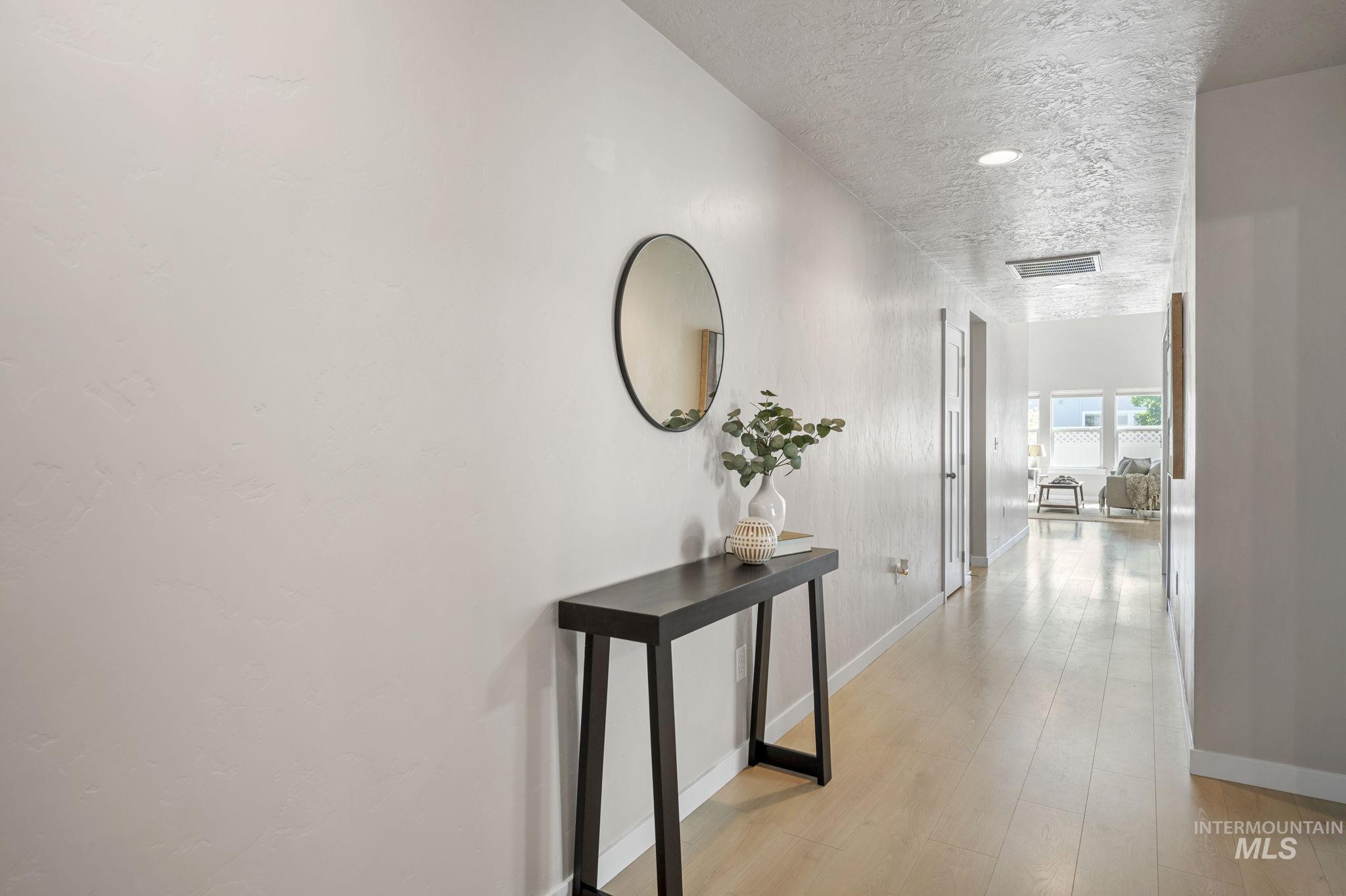 Corridor with a textured ceiling, light wood-style flooring, and recessed lighting