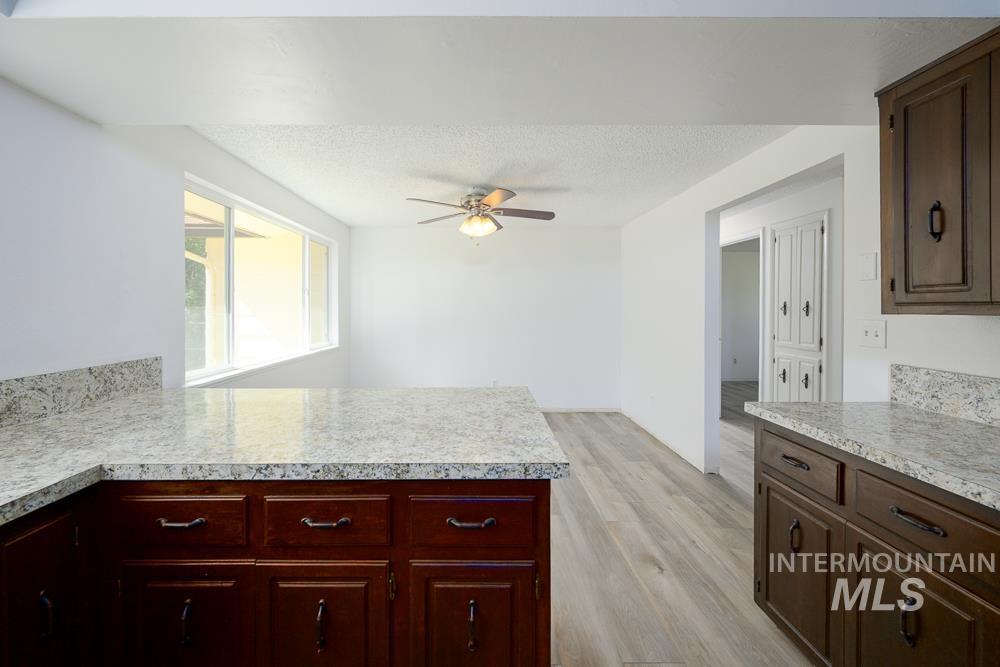 Kitchen featuring light countertops, light wood-type flooring, a textured ceiling, dark brown cabinetry, and a peninsula