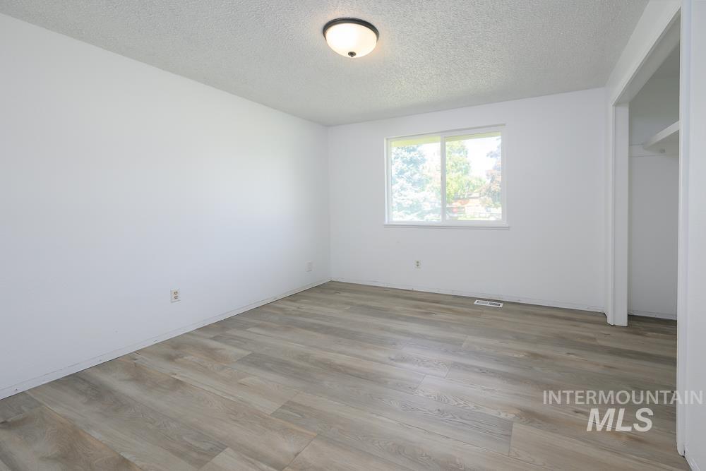 Unfurnished bedroom featuring light wood-style flooring, a textured ceiling, and a closet