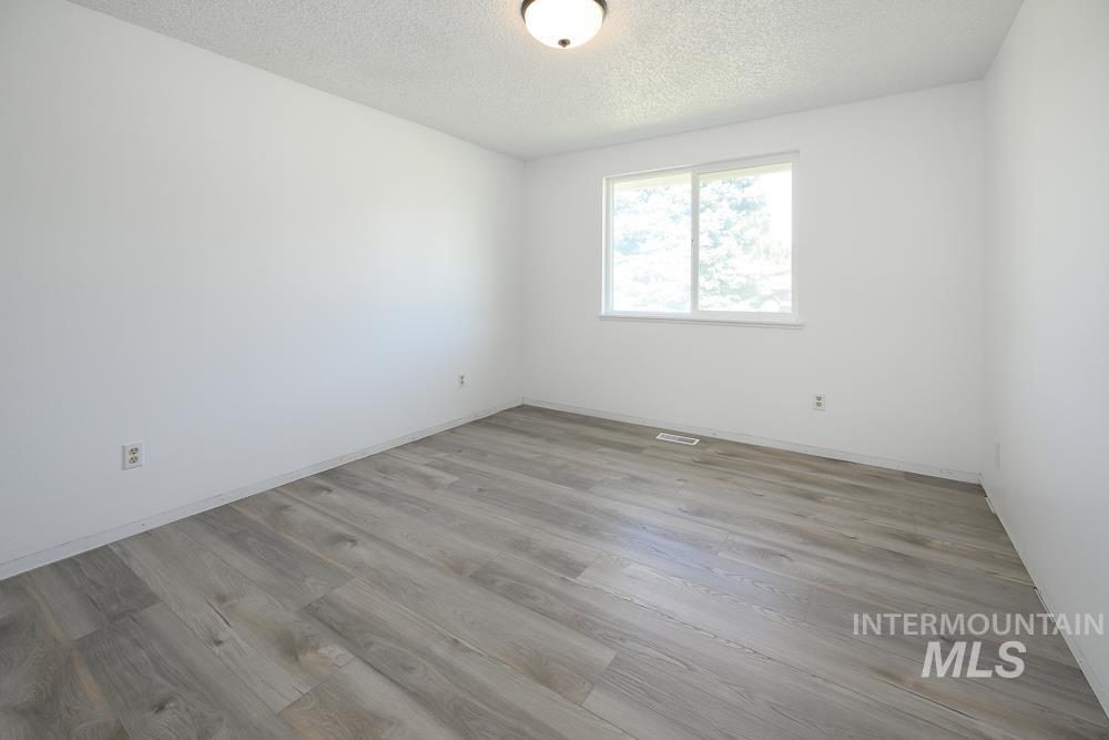 Unfurnished room with light wood-style floors and a textured ceiling
