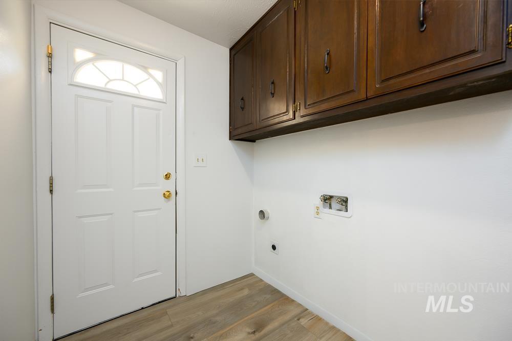 Laundry area with light wood-style floors, cabinet space, hookup for an electric dryer, and washer hookup