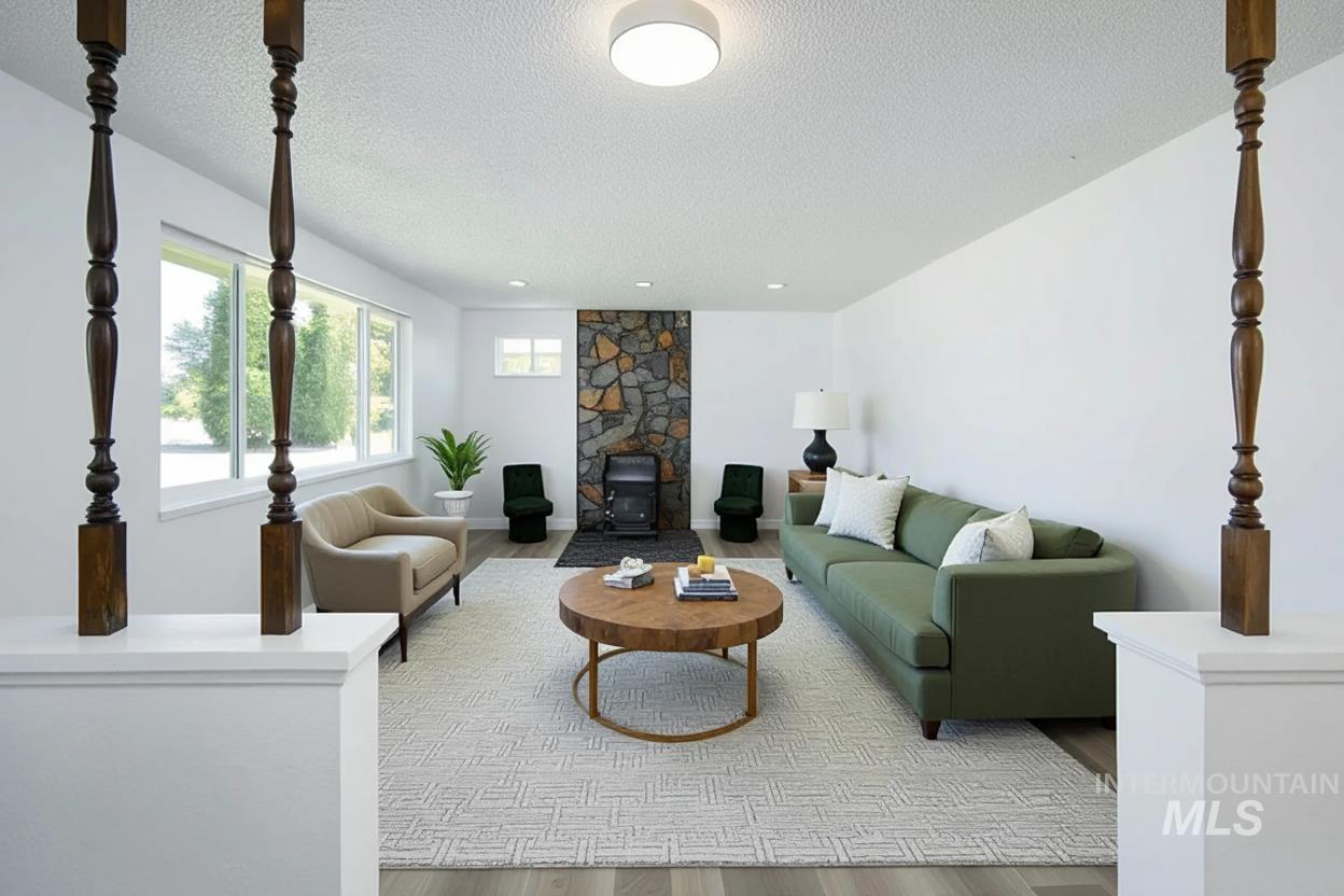 Living room featuring light wood finished floors, a wood stove, and a textured ceiling