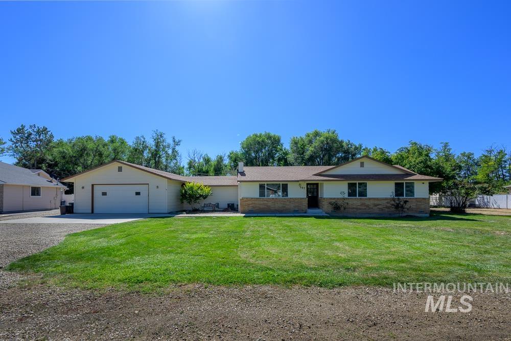 Ranch-style home featuring driveway, a garage, and a front lawn