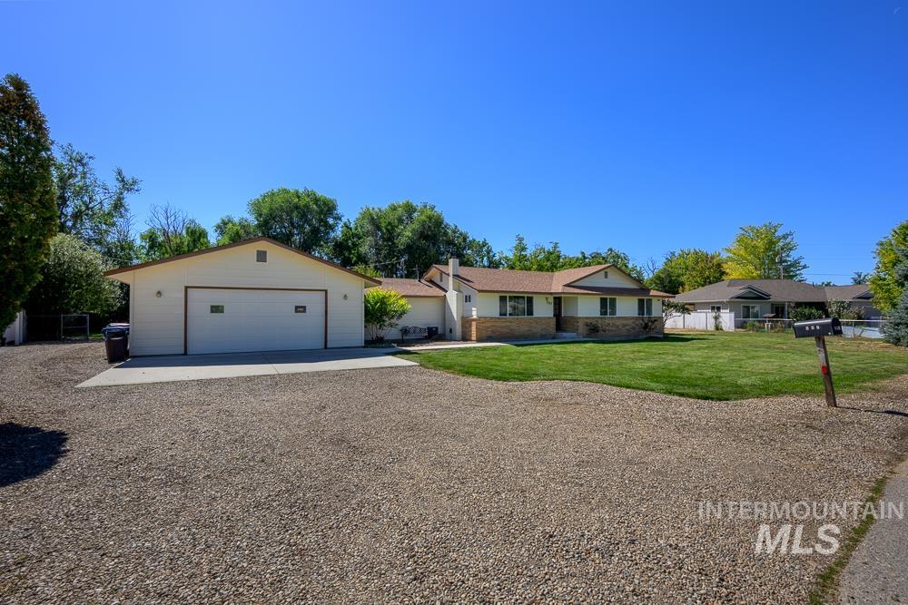 Ranch-style house featuring a garage, gravel driveway, and brick siding