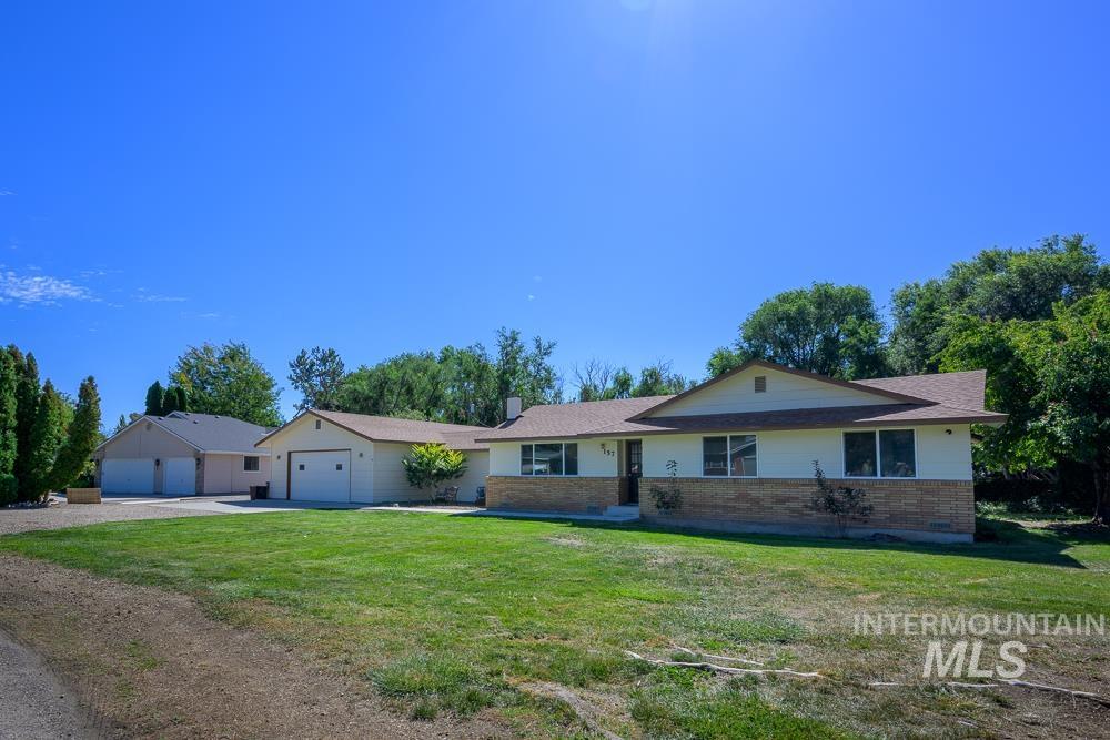 Single story home with brick siding, a front yard, driveway, an attached garage, and a shingled roof