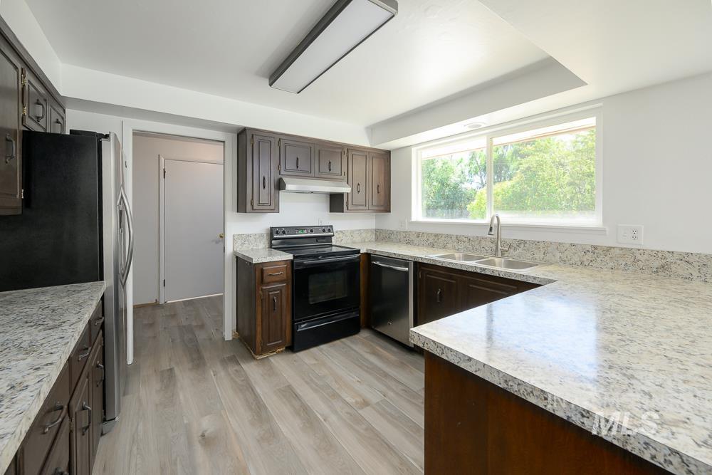 Kitchen featuring stainless steel appliances, light countertops, light wood-style flooring, and dark brown cabinets