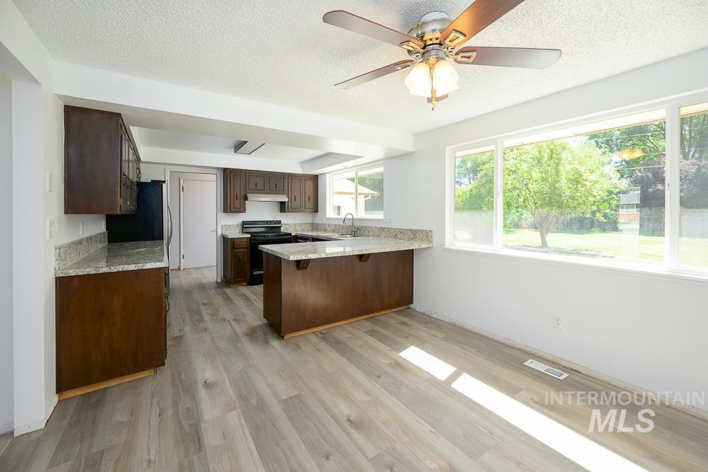 Kitchen with a peninsula, electric range, light wood-style flooring, a textured ceiling, and a breakfast bar
