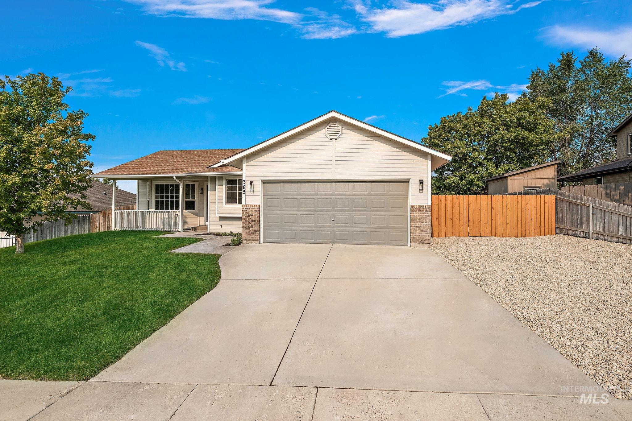 Single story home with driveway, brick siding, covered porch, and a garage