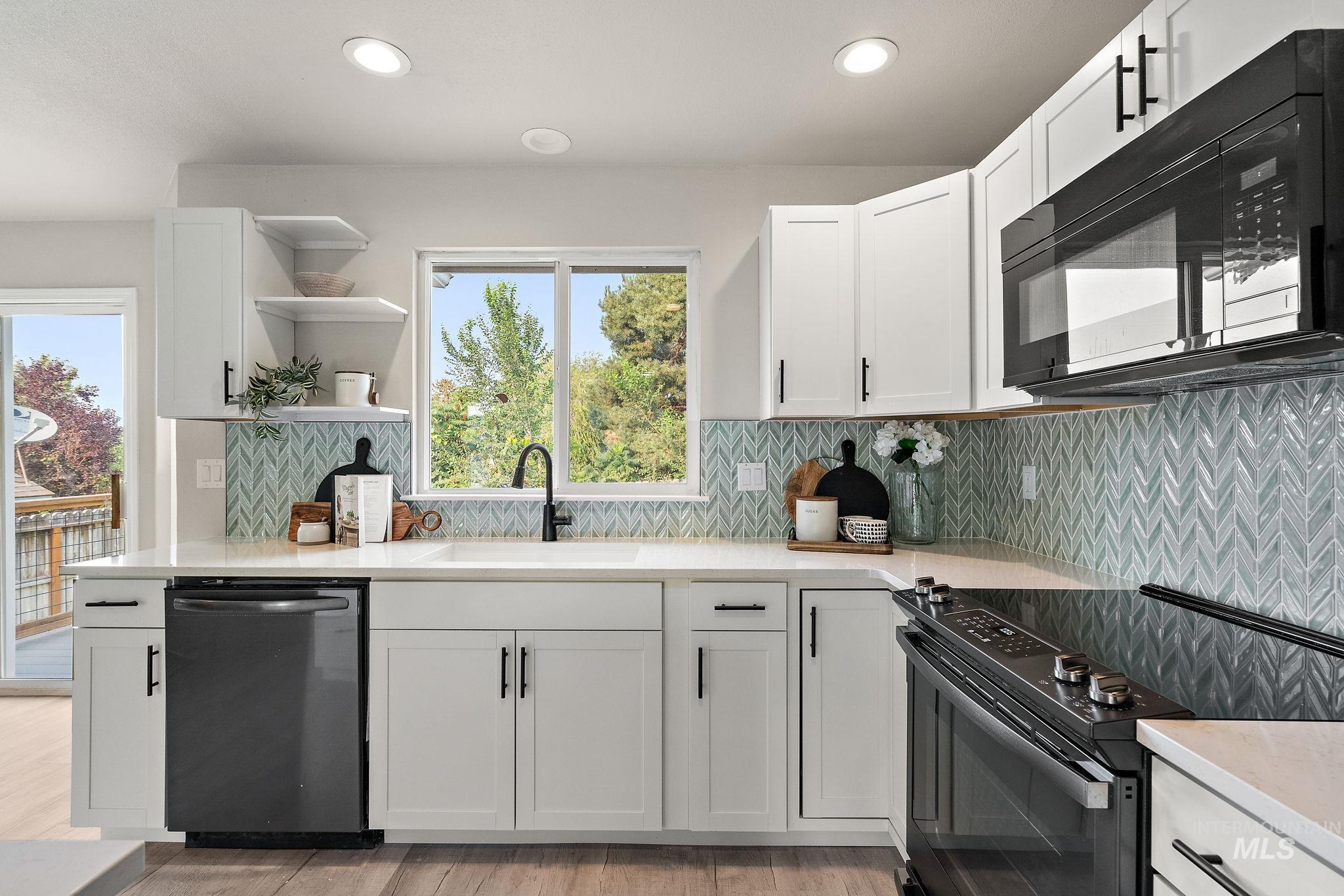Kitchen featuring black appliances, decorative backsplash, white cabinetry, and recessed lighting