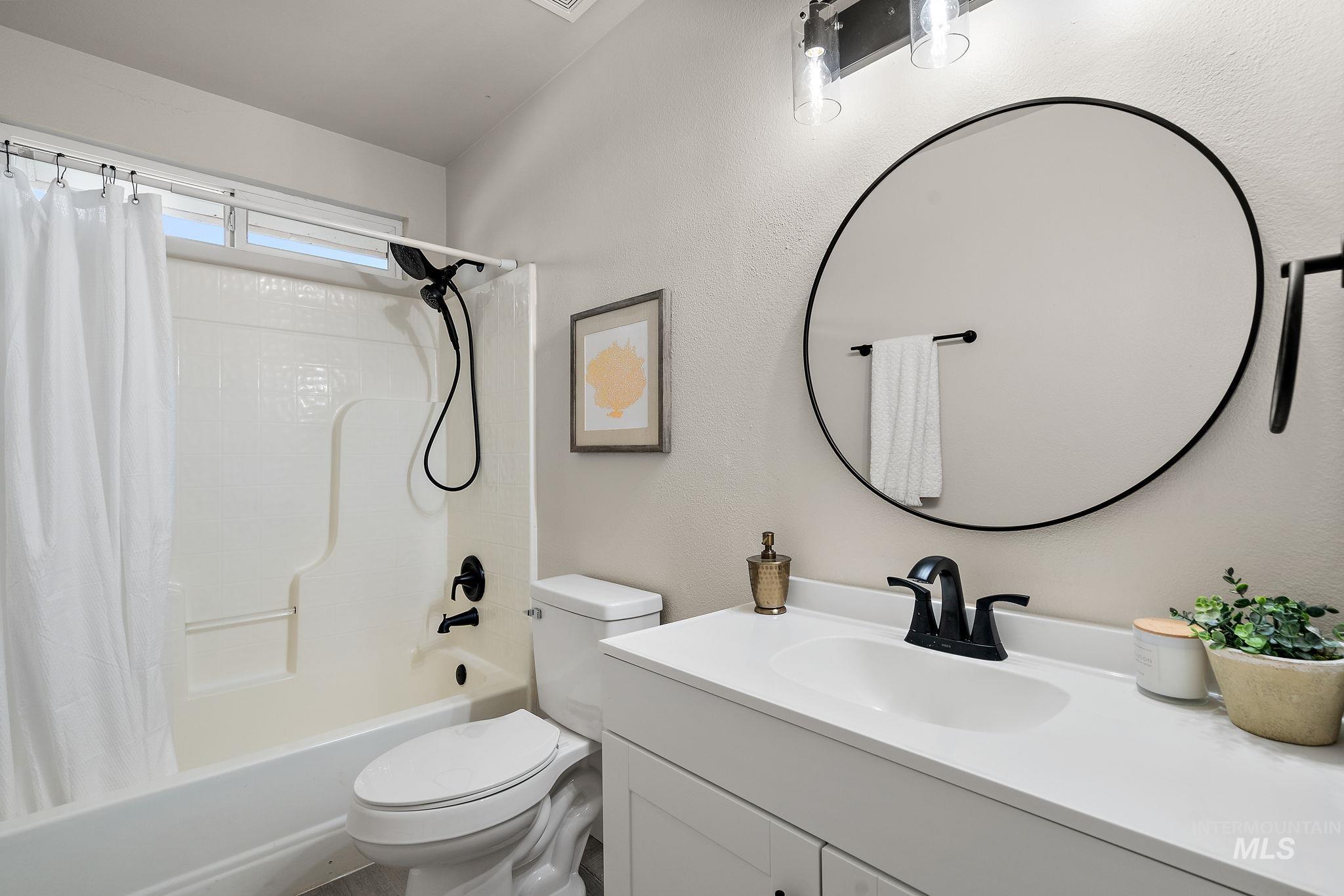 Bathroom featuring shower / bath combo with shower curtain, vanity, and a textured wall