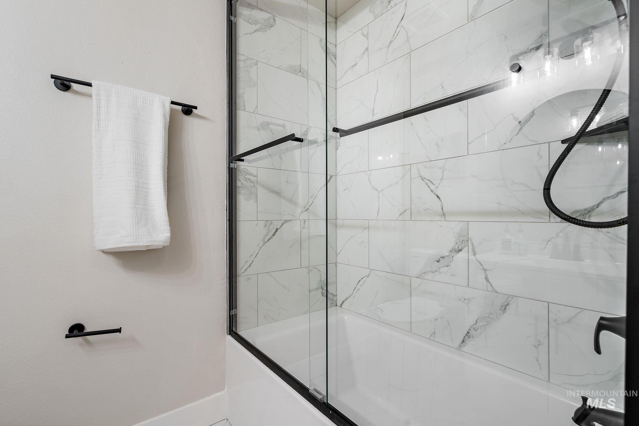 Full bathroom with combined bath / shower with glass door and baseboards