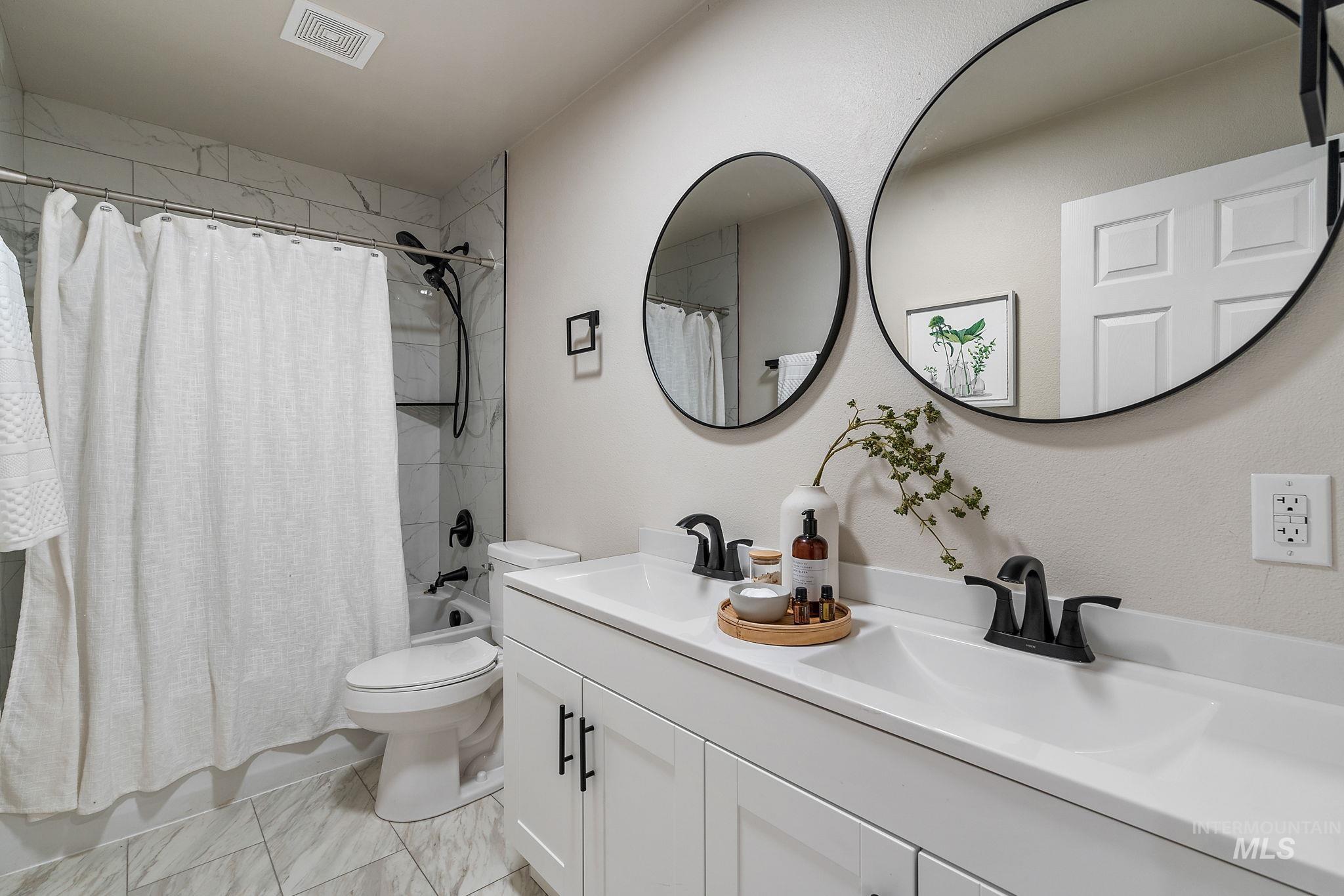 Bathroom featuring shower / bath combo with shower curtain and double vanity