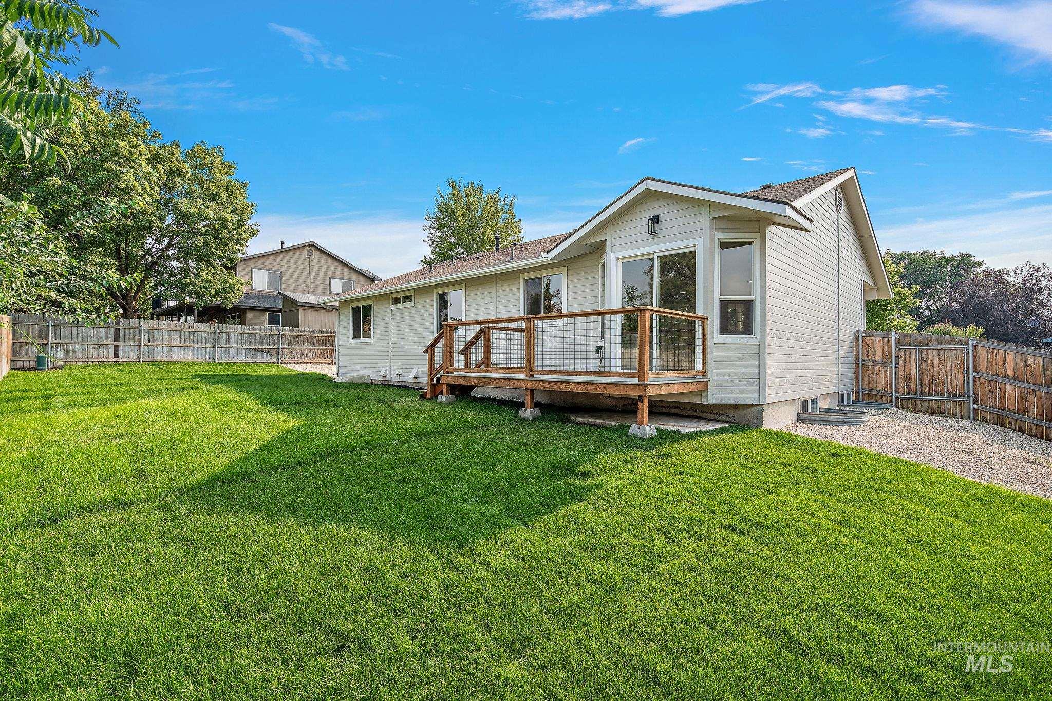 Rear view of house with a fenced backyard, a wooden deck, and roof with shingles