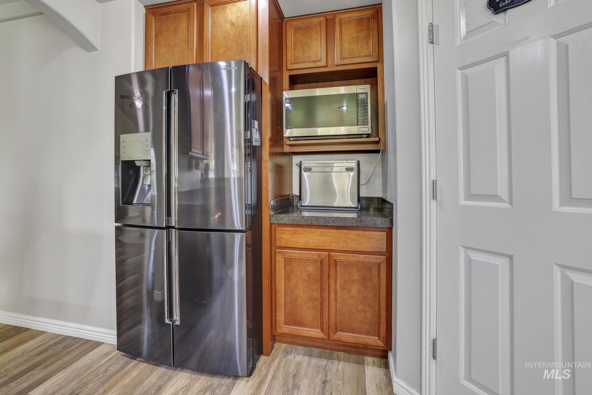 Kitchen with brown cabinetry, stainless steel appliances, and light wood-type flooring