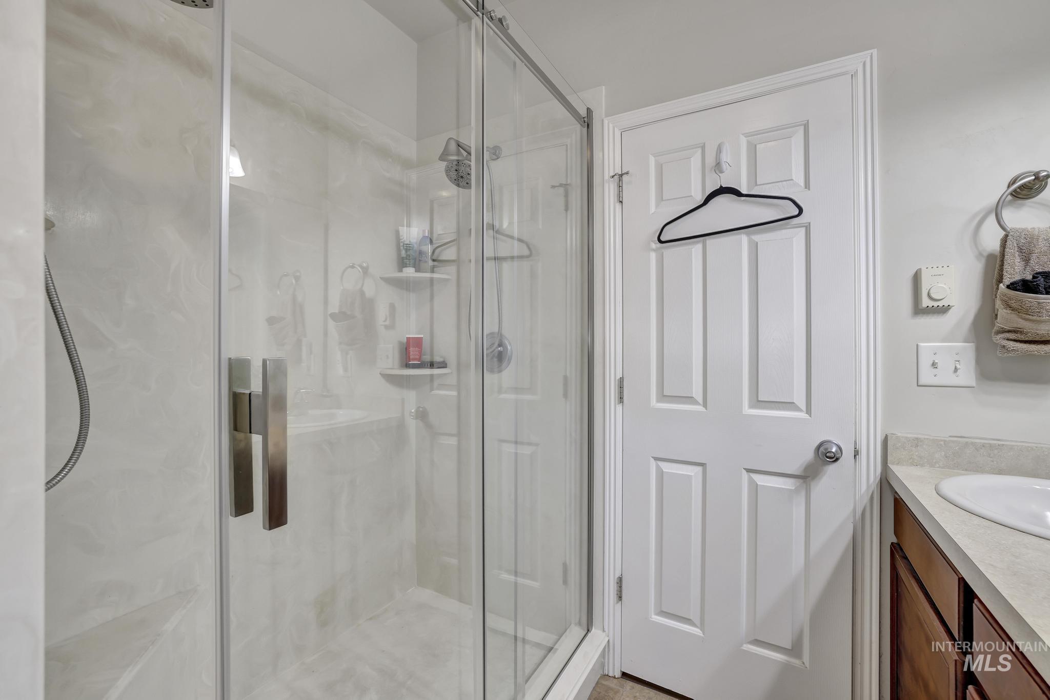 Full bath featuring vanity and a marble finish shower