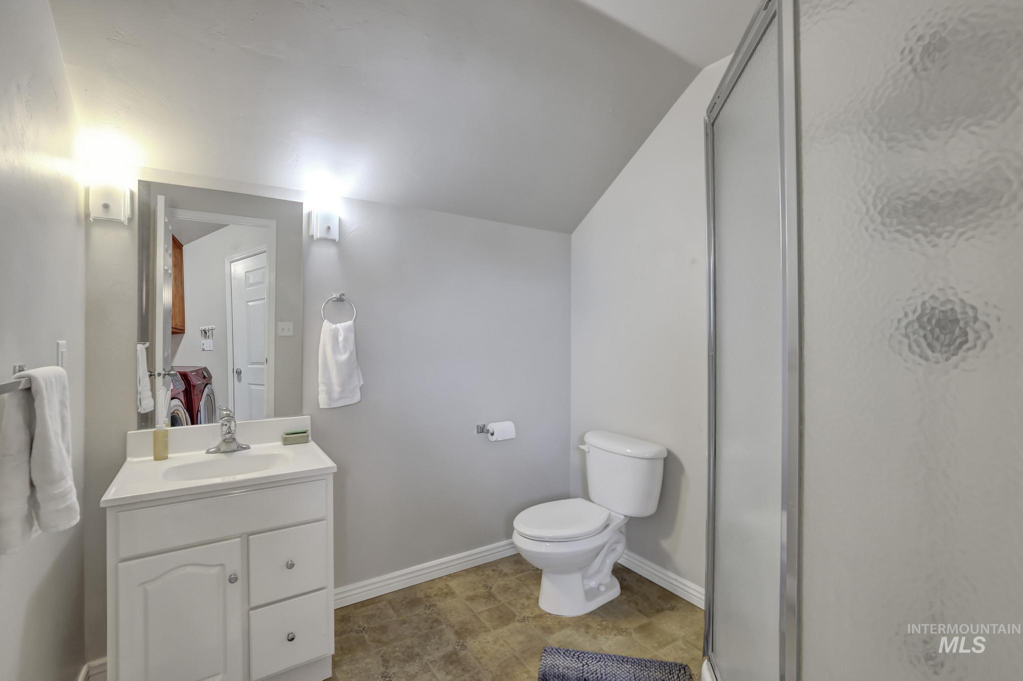 Full bath featuring vanity, a shower stall, and vaulted ceiling