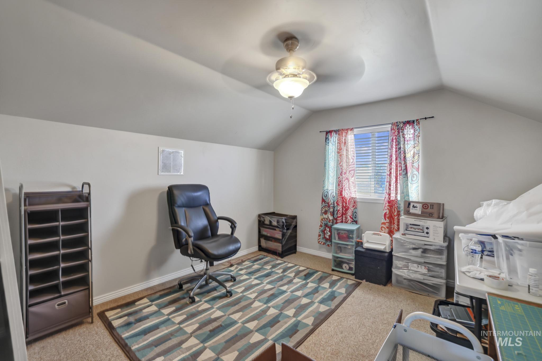 Home office with lofted ceiling, light carpet, and ceiling fan