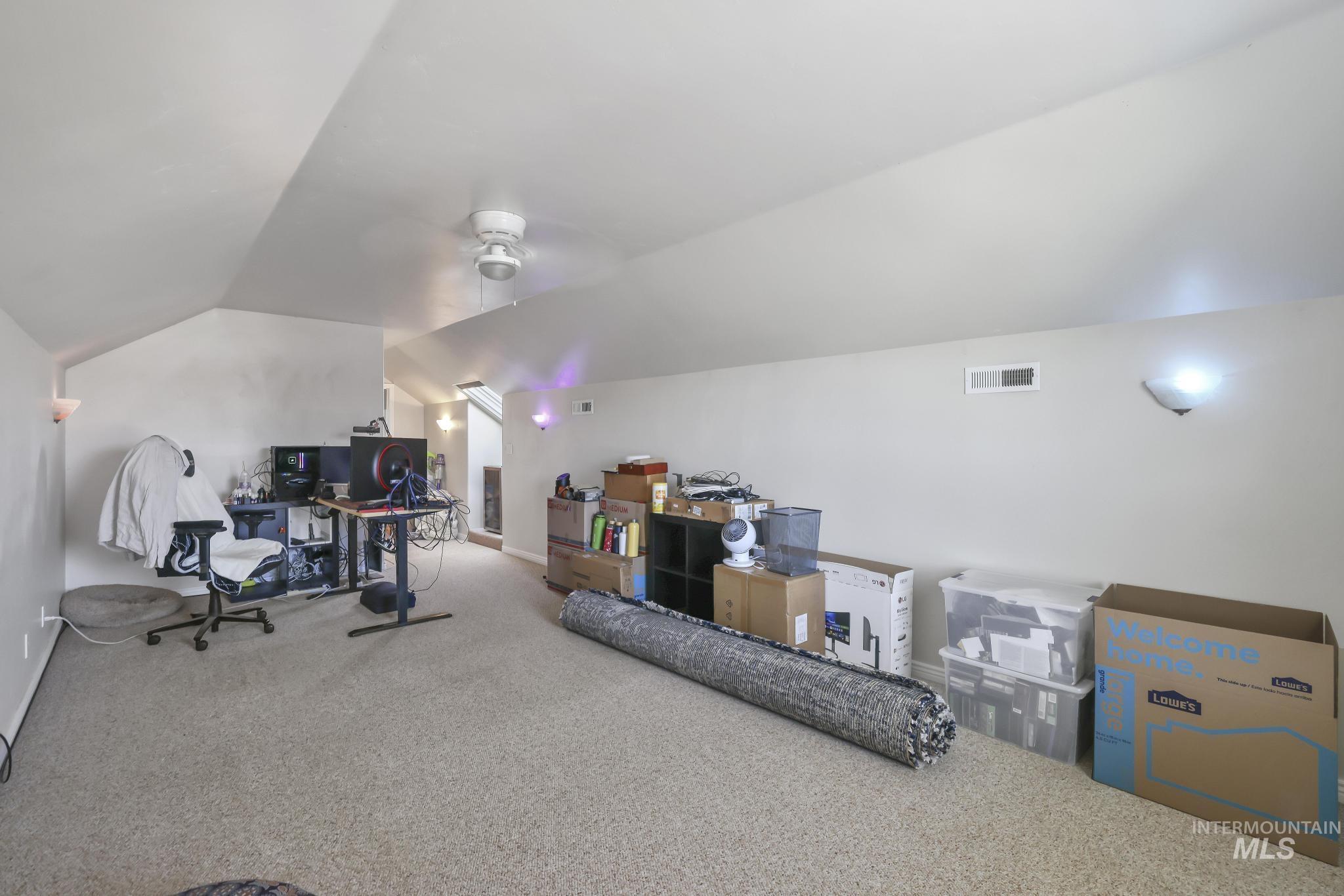 Office area with carpet floors, vaulted ceiling, and a ceiling fan
